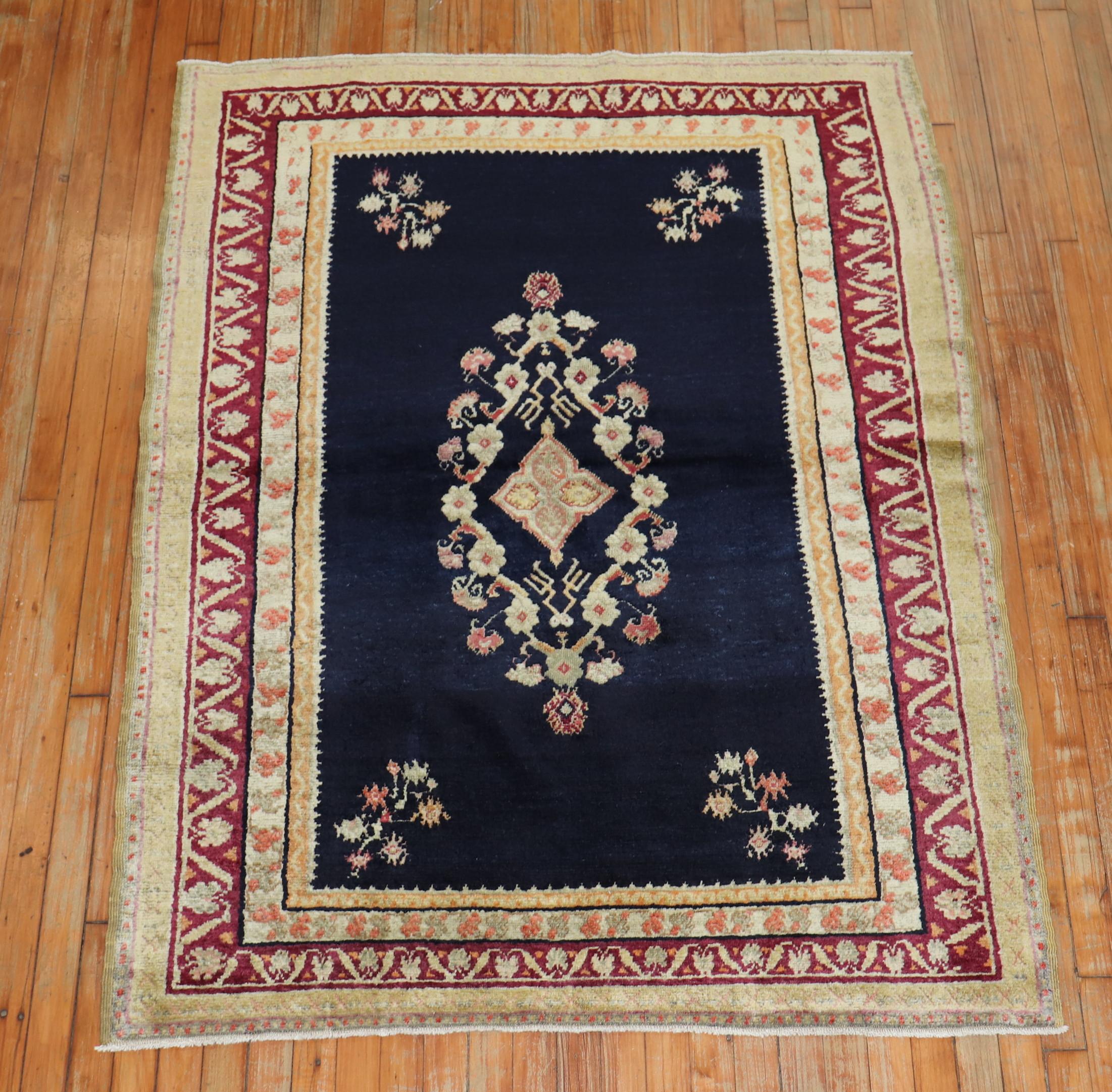 An early 20th century fine Turkish Ghiordes rug featuring an elegant floral motif with a navy ground, accents in peach, ivory, pink, the main border is raspberry, circa 1900.

Measures: 4'4'' x 5'10''.