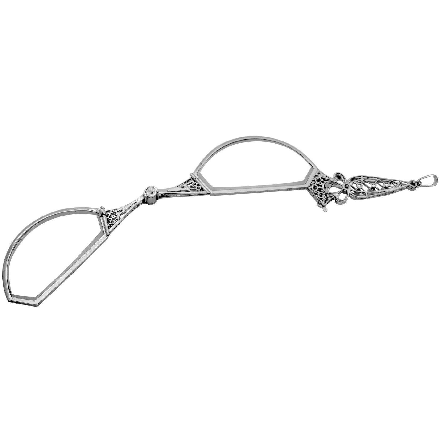 The perfect accessory:  a uniquely-shaped lorgnette.  When closed, it forms a circle; when opened, has two demi-lune shaped magnifying lenses.  14K white gold.  The openwork handle is encrusted with rose diamonds.  Charming, elegant and practical. 