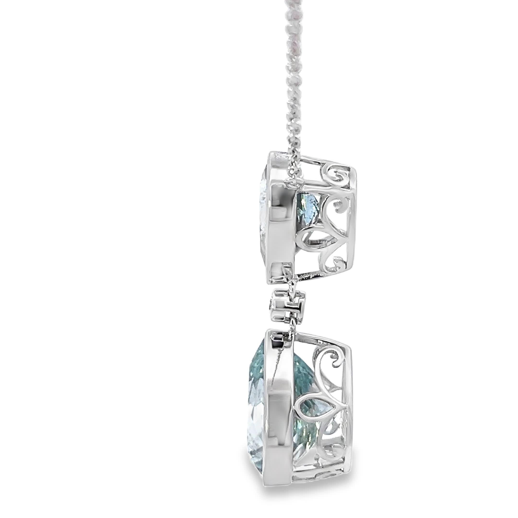 Questo splendido ciondolo con gemme color acqua presenta due squisite pietre a forma di goccia, sospese con eleganza da una delicata catenina. L'intricato design è completato da uno scintillante accento di diamanti, che lo rende un accessorio