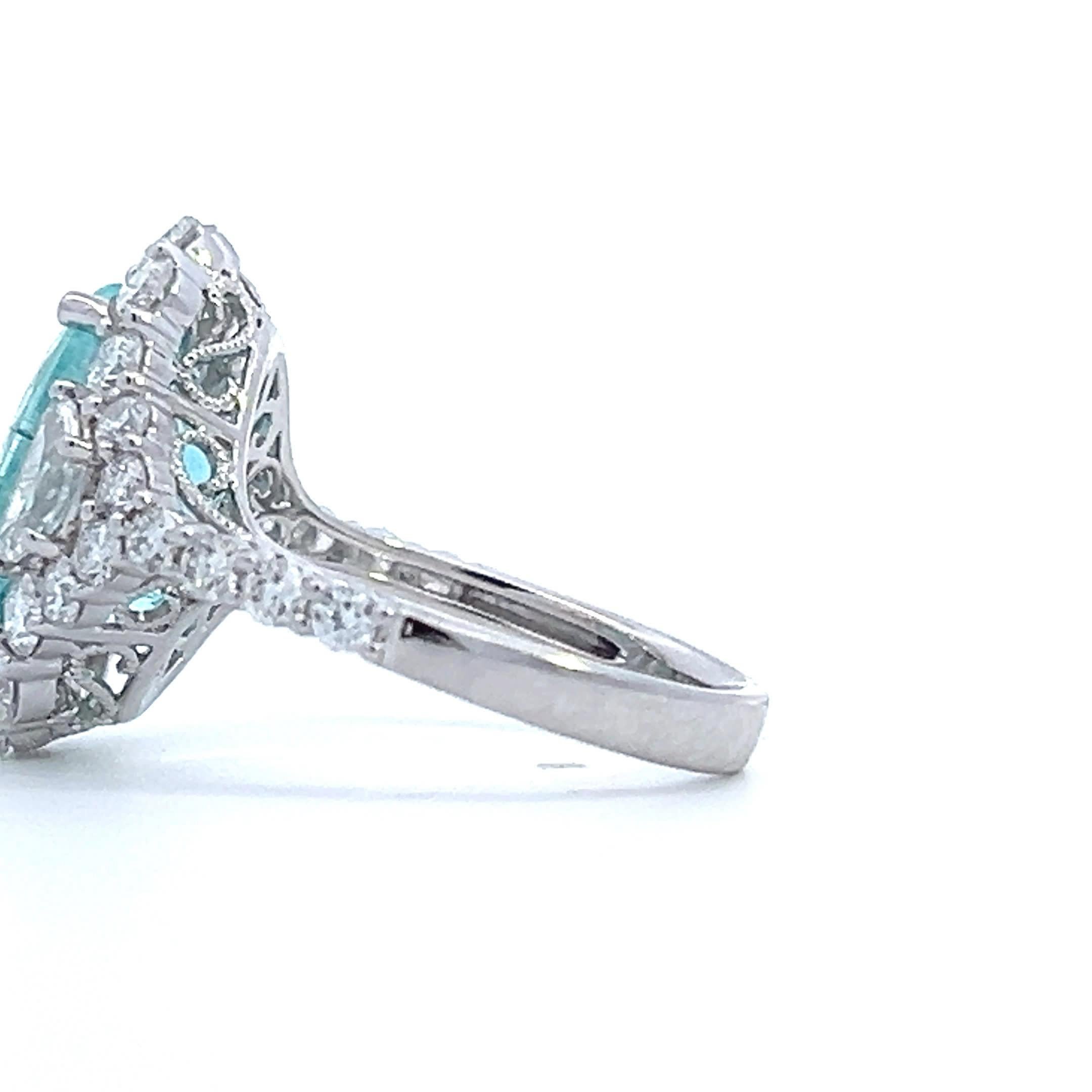 Dieser exquisite Ring zeigt einen atemberaubenden Aquamarin-Edelstein, der von einem Heiligenschein aus funkelnden Diamanten umgeben ist. Das filigrane Design und der brillante Glanz machen ihn zur perfekten Wahl für alle, die Eleganz und Raffinesse