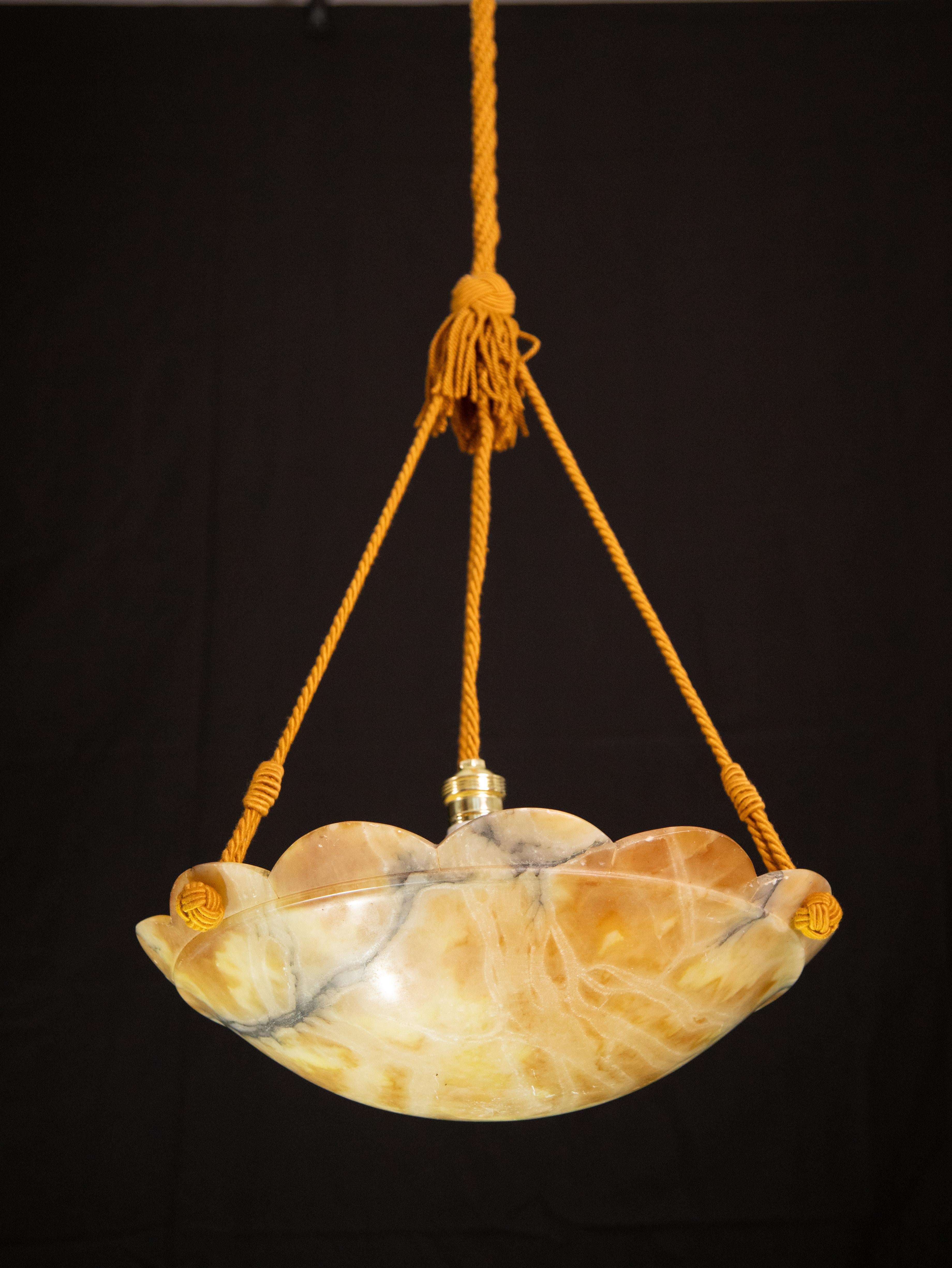 Antique orange alabaster hanging chandelier in Art Deco style, circa 1950s.
A unique piece in orange alabaster, beautifully worked with hues and reflections of other colors when lit, still suspended from the three original chains.
The light that