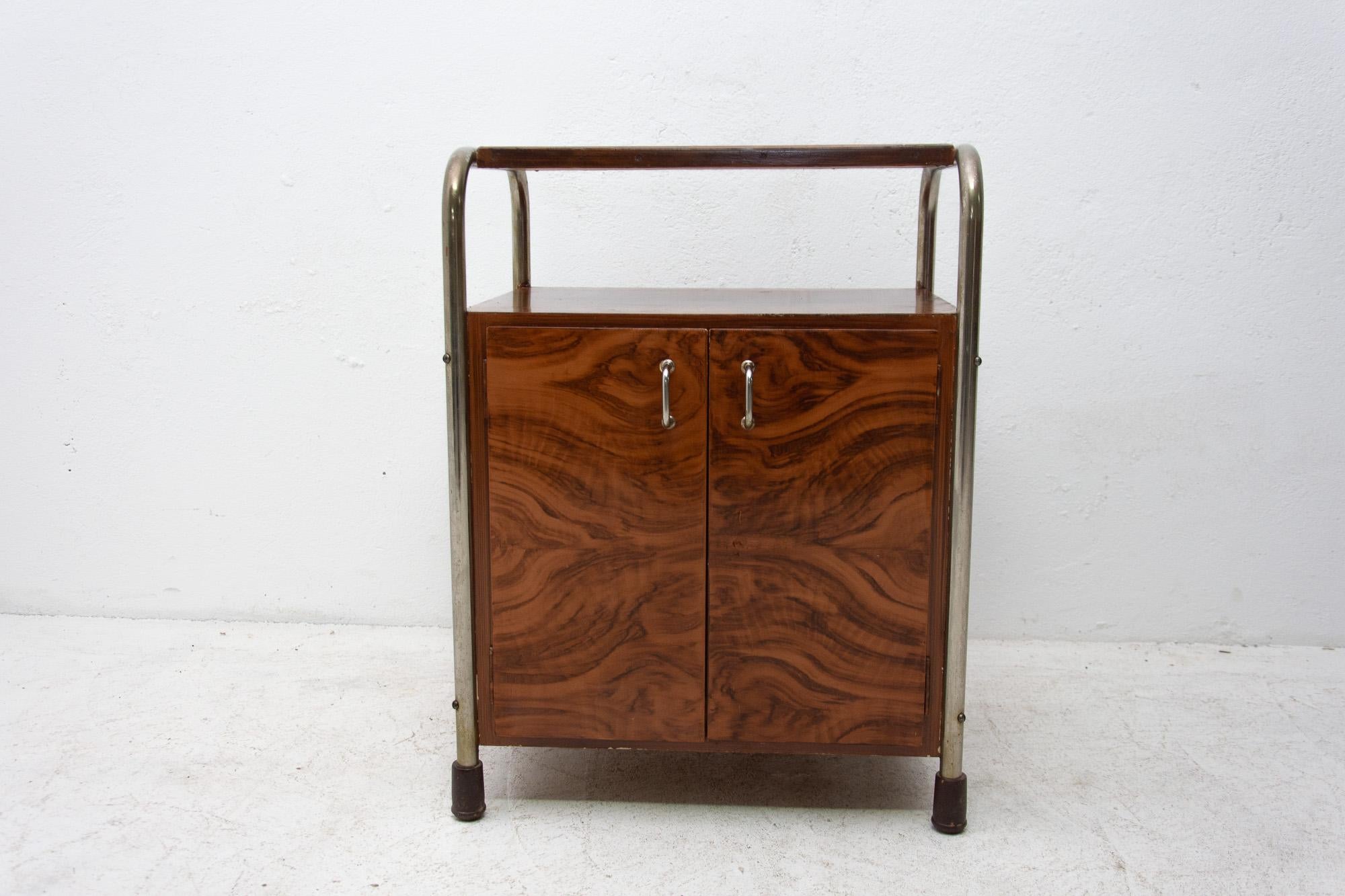 Bohemian chromed side table or nightstand in polished walnut was made in the 1930s. It features a very simple and practical design. Standing on a chrome base. It´s a nice example of Central European functionalist furniture design. The cabinet has