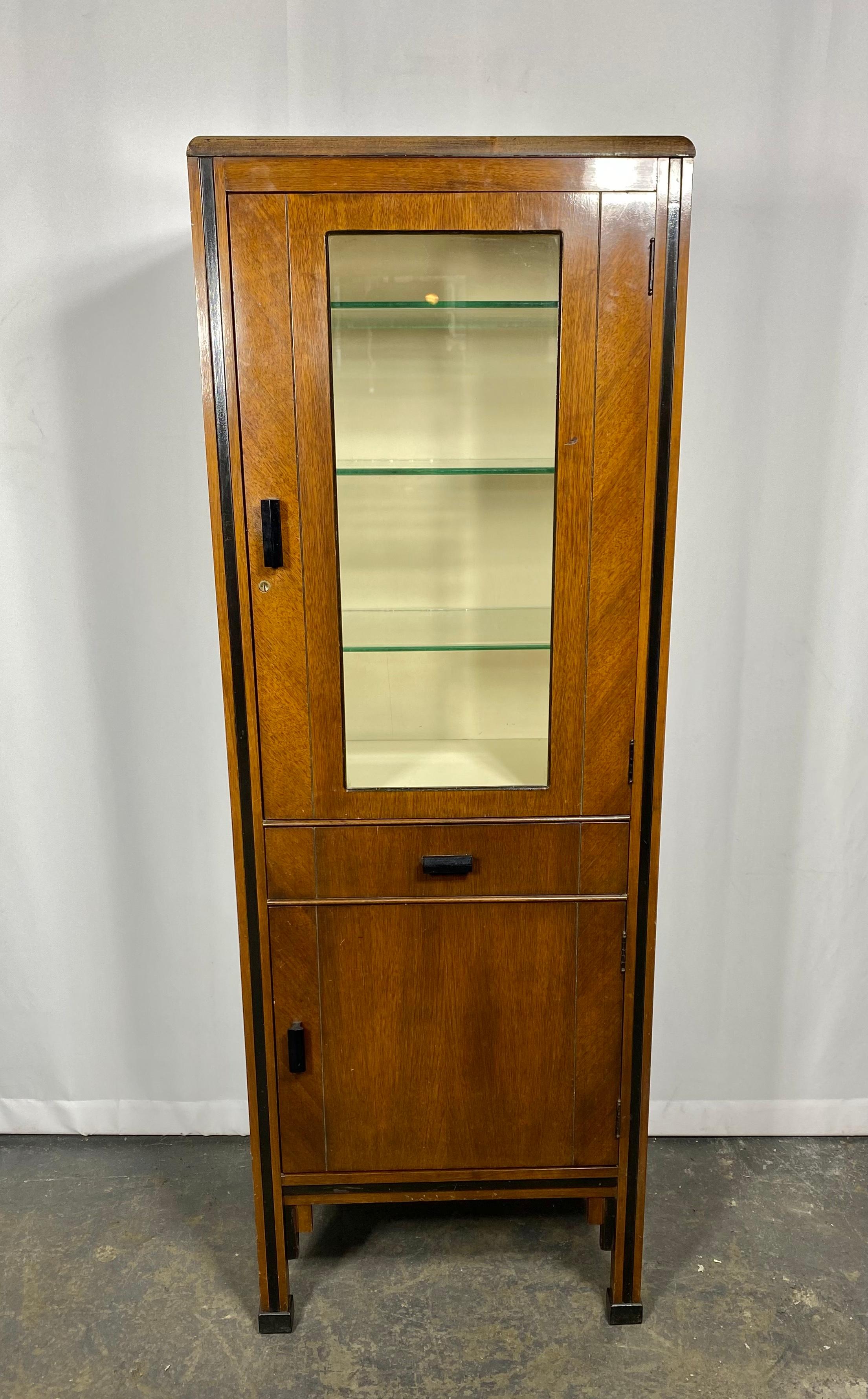 Elegant Art Deco Dental cabinet, walnut and glass, manufactured by ENOCHS,, Great decorative item,, perfect scale.. Be wonderful in a bathroom , kitchen entry space, Classic Art deco ,, modernist . streamline design,, Black lacquer details.. Hand