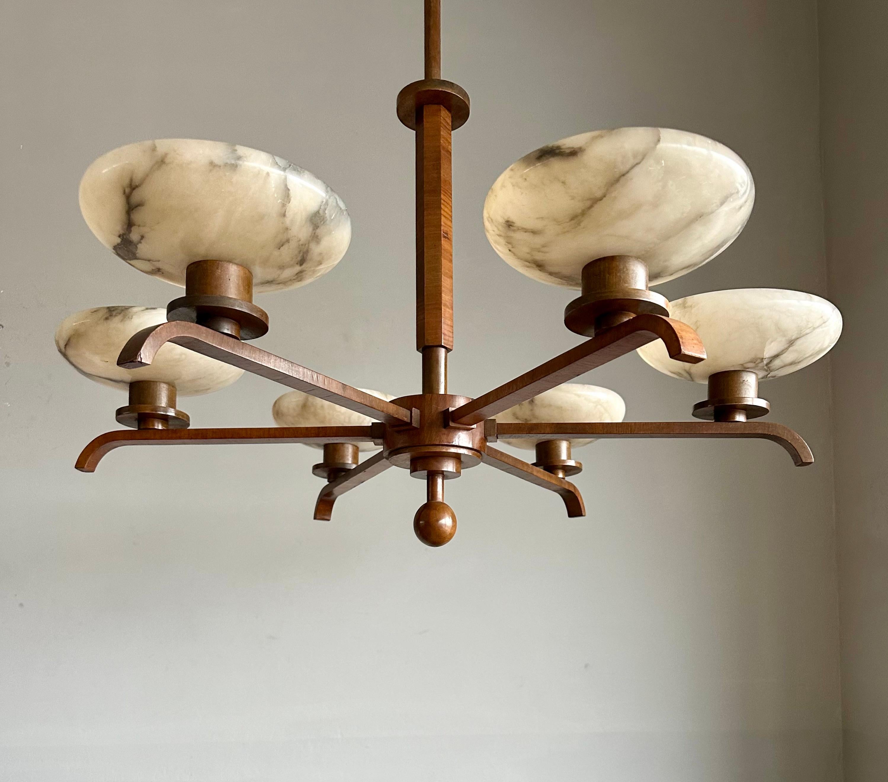 This also unique and large size, eye pleasing Art Deco chandelier, stands out for several reasons:

Firstly, it has a stunning & solid, nutwood veneered 'body' which is in very good condition. 
Secondly, its perfect Art Deco design makes it a true