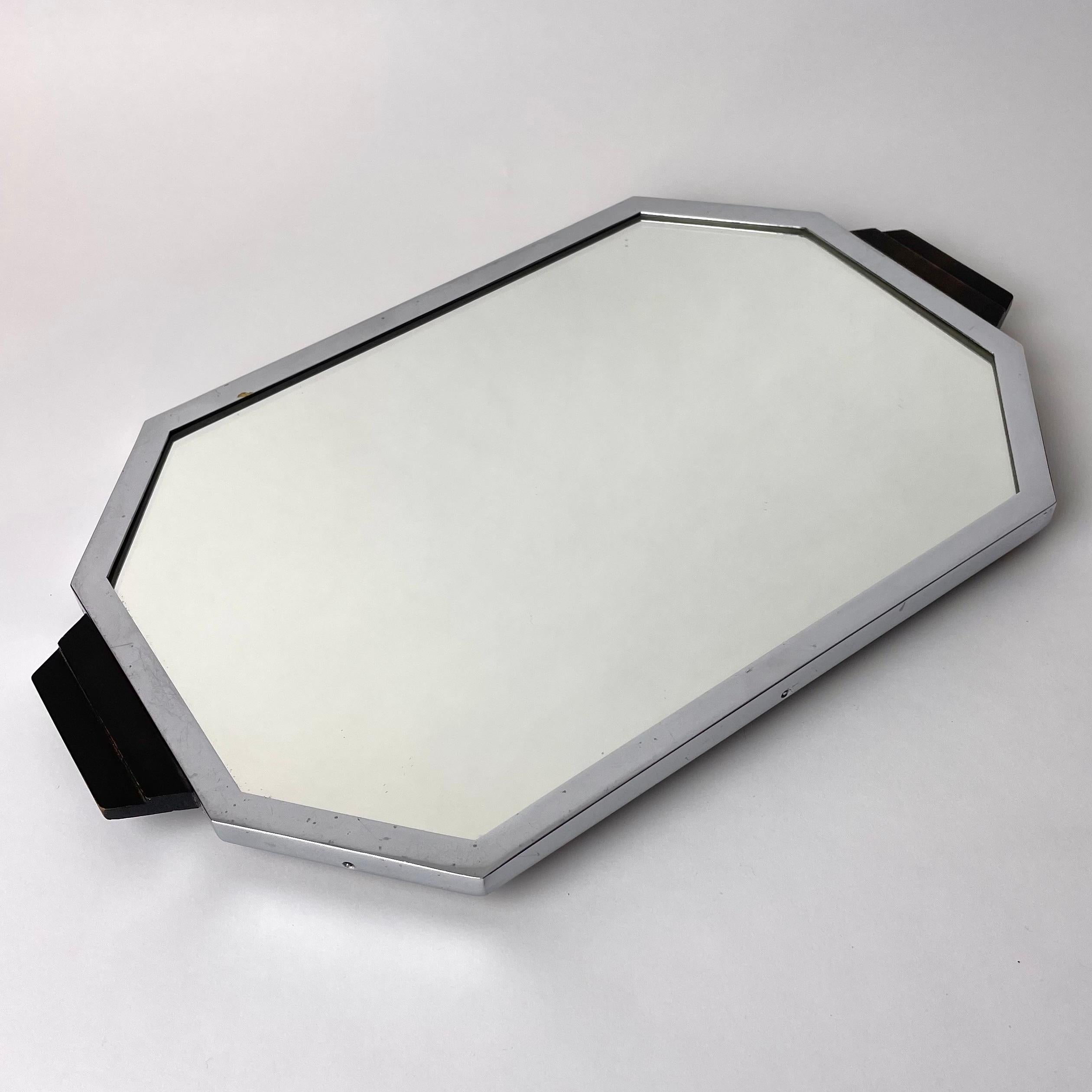 An Elegant Art Deco Tray in Chrome and Blackened Wood with Mirror Glass, 1920s.

This elegant and refined chrome and mirror tray with blackened wood handles reflect the sensibilities and aesthetic interests of the Art Deco period. Modern materials