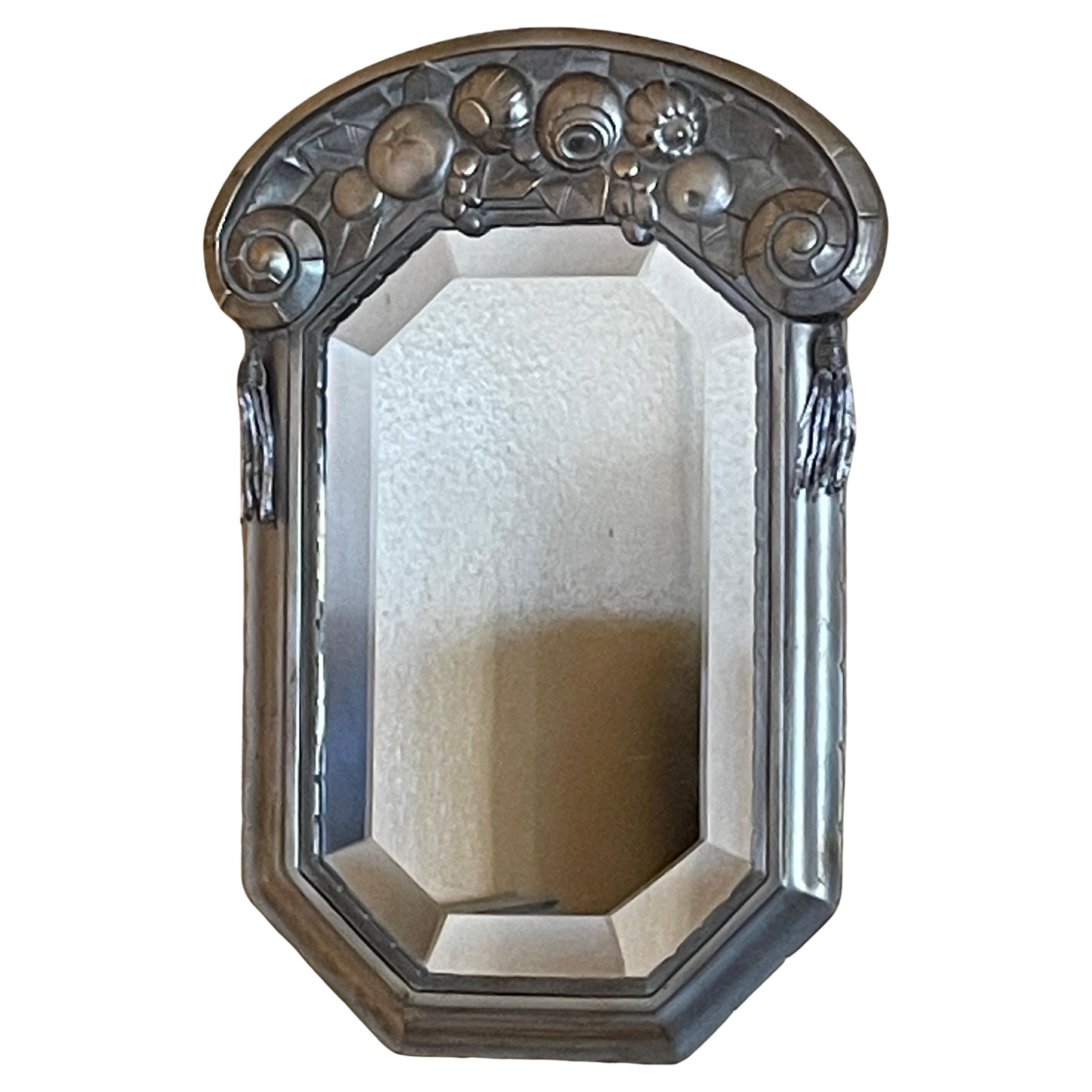 Eleganter kleiner Art Déco-Spiegel.
Design 1920er Jahre. Frankreich. Art Déco-Stil.
Spätere Version.
Rahmen aus versilberter Bronze .
Geometrische achteckige Form.
Stilisiertes florales Motiv.
