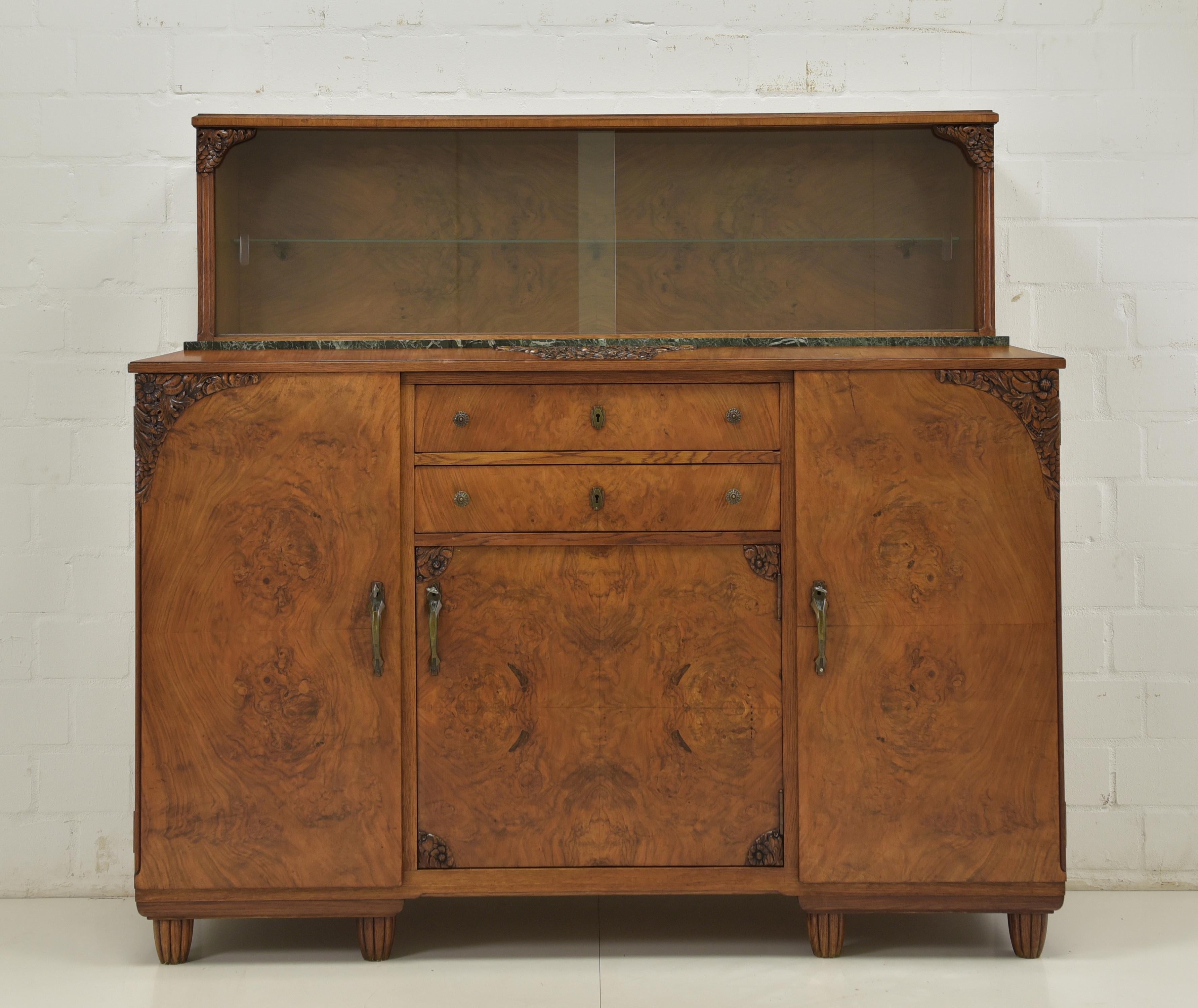 This elegant Art Deco sideboard with glass top is a timeless piece of furniture from around 1925. It is in very good condition and has a high-quality finish.


The sideboard is made of walnut veneer with an oak frame. The base has three doors and