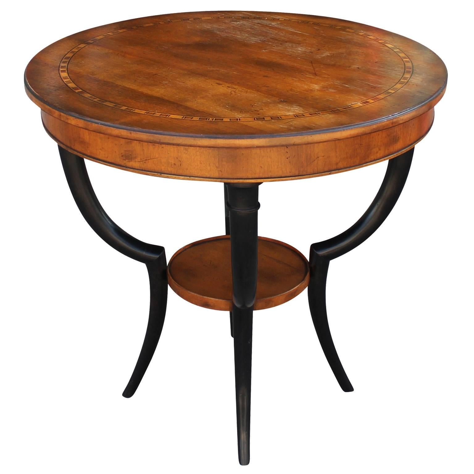 Beautiful occasional table by Baker. Two-tone round table has elegant swooping lines. Top is accented with a delicate band of inlaid wood.