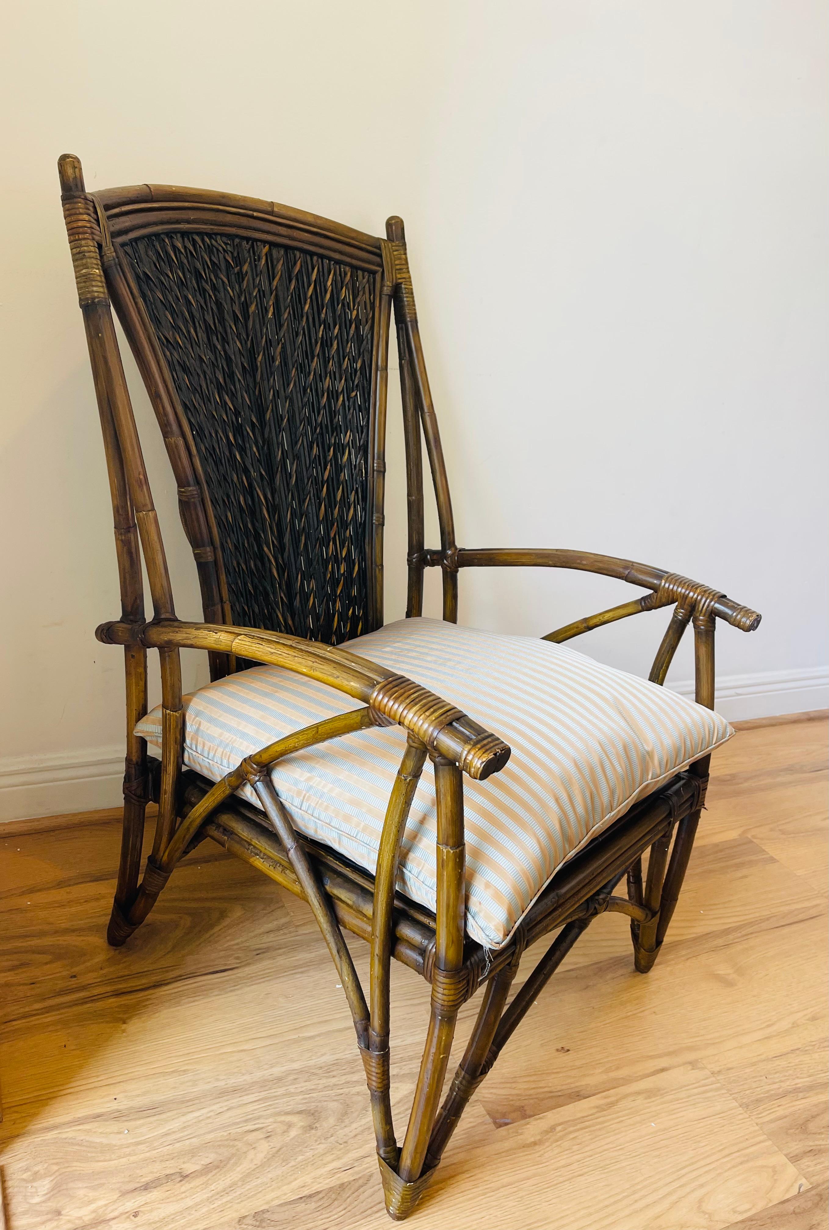 Elegante sillón vintage de bambú patinado con mimbre tejido. Almohada de plumón de seda a rayas.