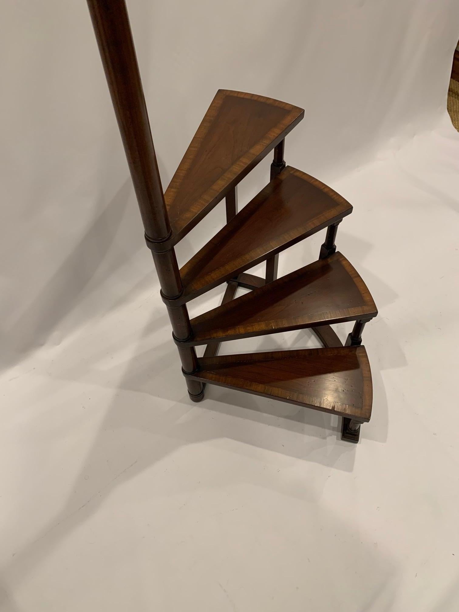 Lovely banded mahogany library steps having an elegant spiral shape, 4 steps, and columnar handle with finial at the top. Meant to be used for display, or as an artful freestanding sculptural piece, not as functional steps.