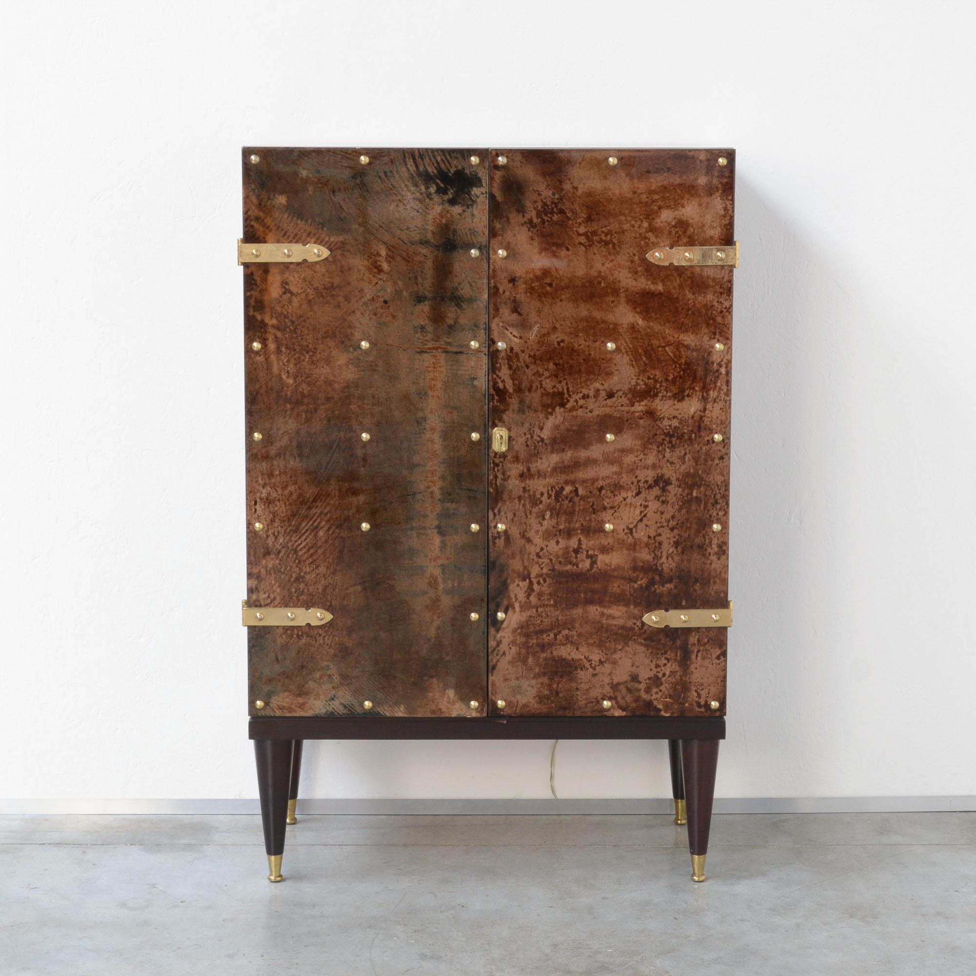 This elegant exclusive bar cabinet was designed by the Italian furniture designer Aldo Tura and can be dated in the late 1950s.
The wooden cabinet is finished with brown colored and lacquered goatskin, completed with brass details. The base is made
