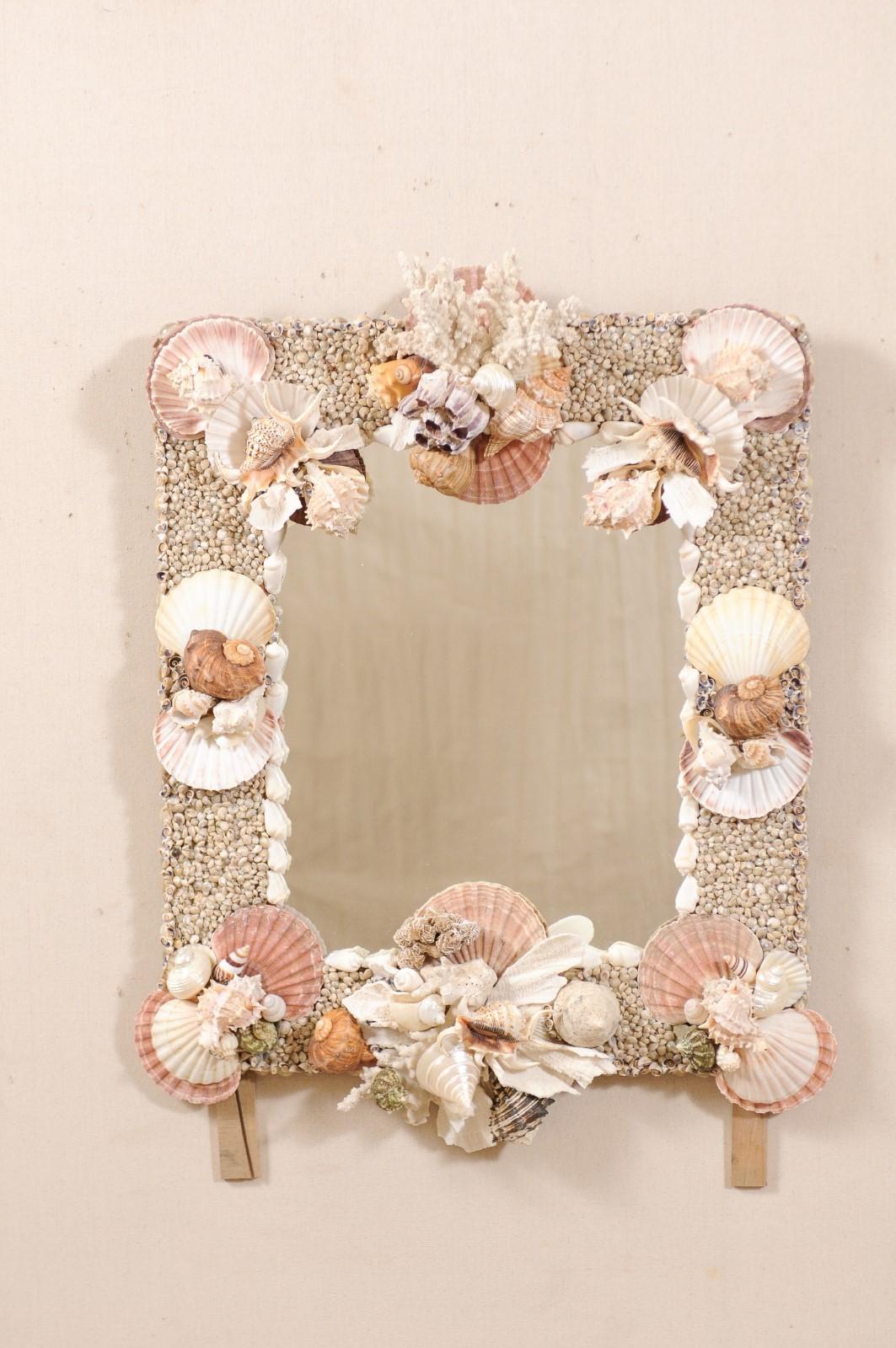 A shell and coral decorated wall mirror. This oceanic inspired mirror, custom fashioned with exquisite attention to detail, is comprised of real sea shells and coral, in various shapes and sizes, which have been artistically hand-wreathed about the
