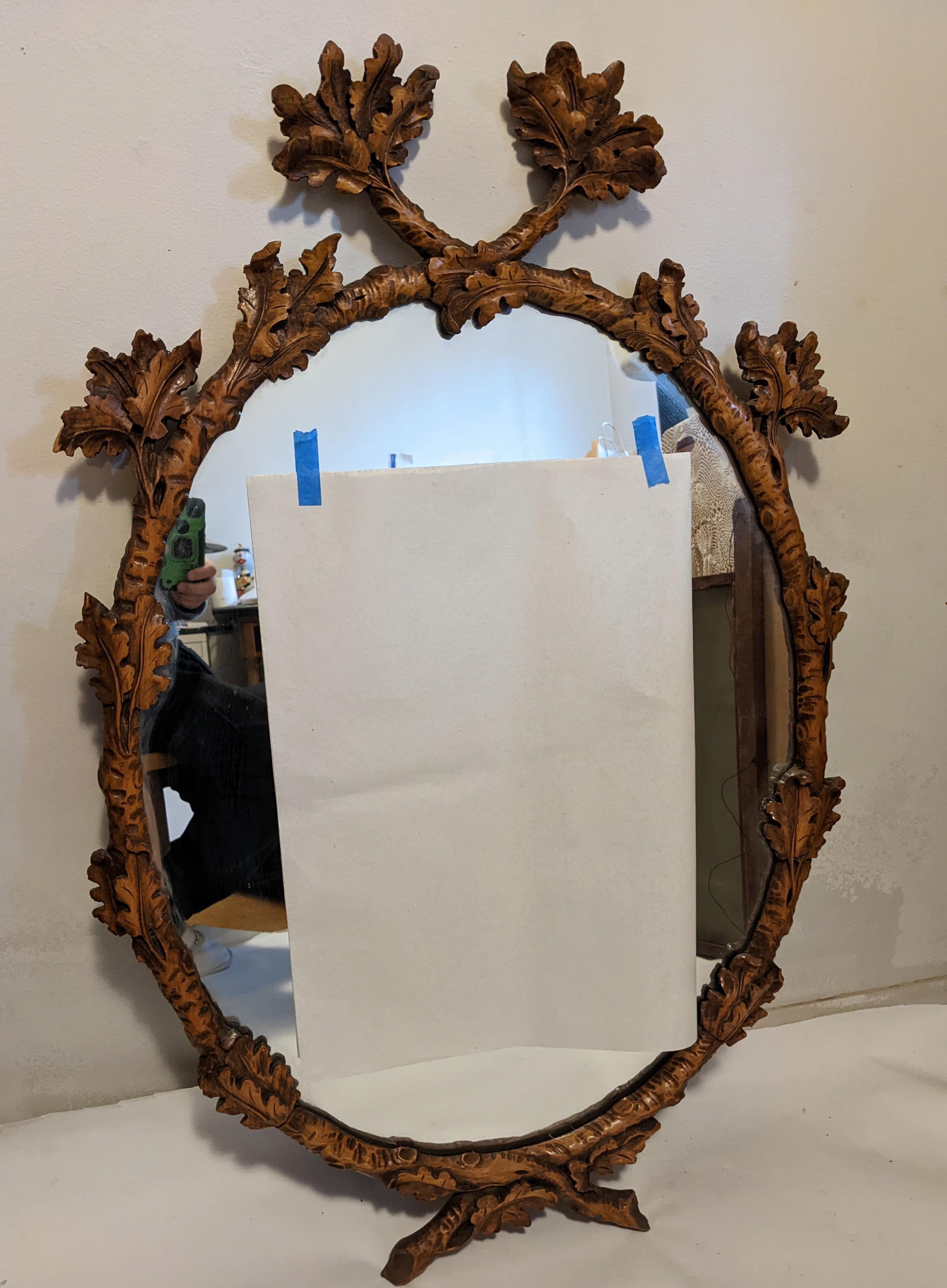 Elegant and impressive Black Forest hand carved oak leaf mirror from Germany 1890's. Beautifully hand carved with a border of oak leaf motifs around which cross on top to form a crown. Lovely warm brown tones.
Very good condition. One small chip