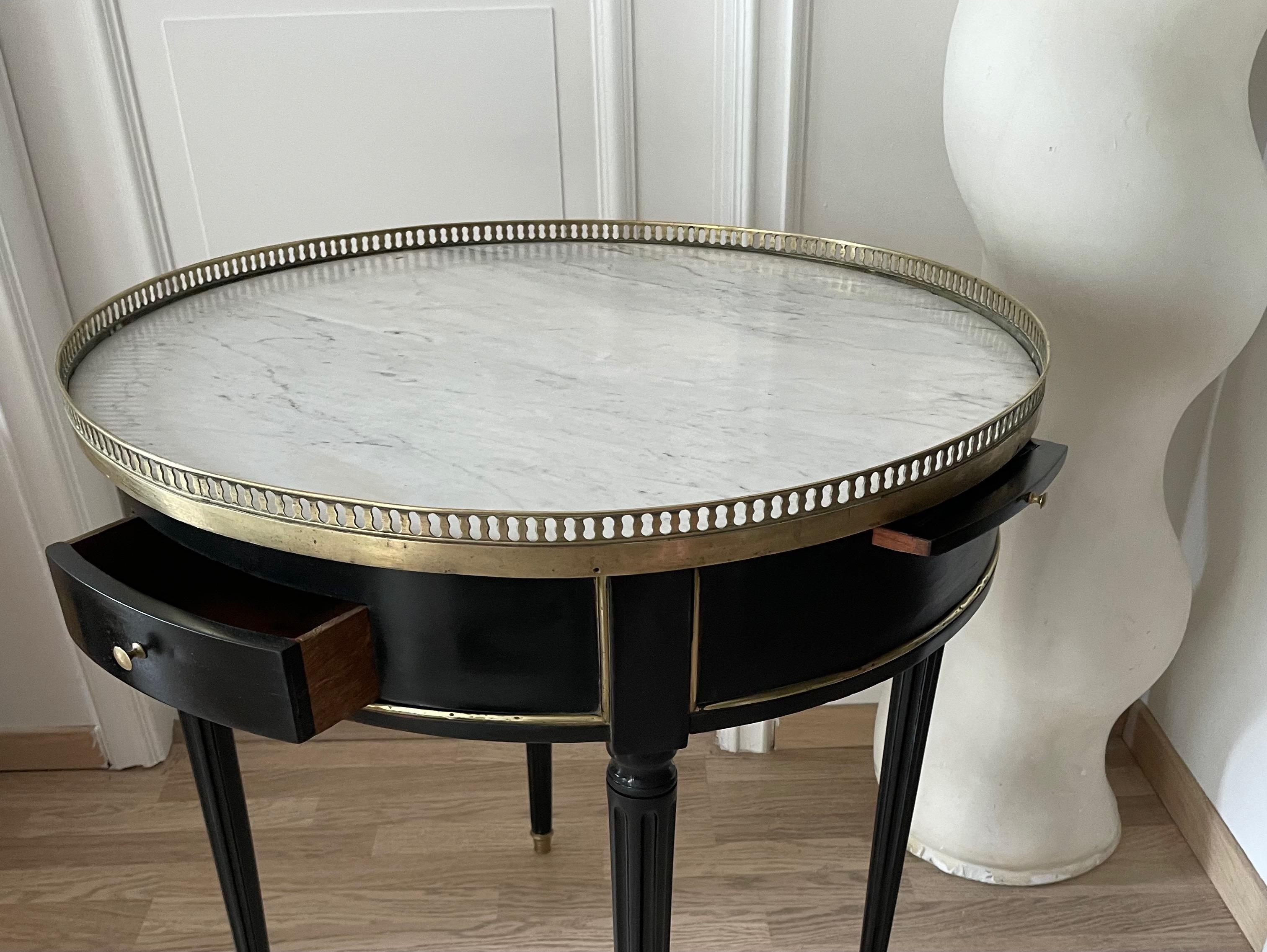 A Louis XVI style black lacquer side table with two drawers, two small shelves with leather, brass details ,marble top and a fine brass openwork gallery.
By Maison Jansen, France 1950.