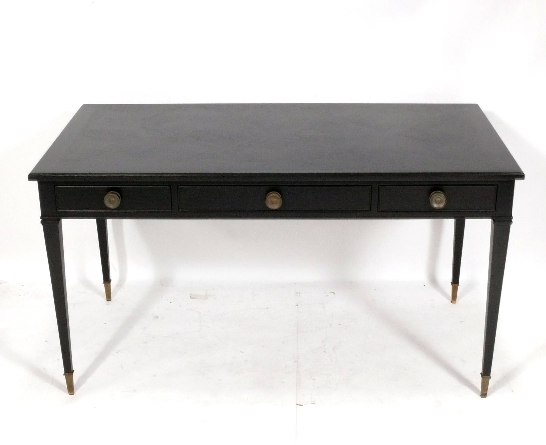 Elegant Black Stained French Style Bureau Plat or Desk by Kittinger, American, circa 1960s. It has recently been refinished in a black stain that still allows you to see the beautiful parquet top. The brass hardware and sabots retain their warm