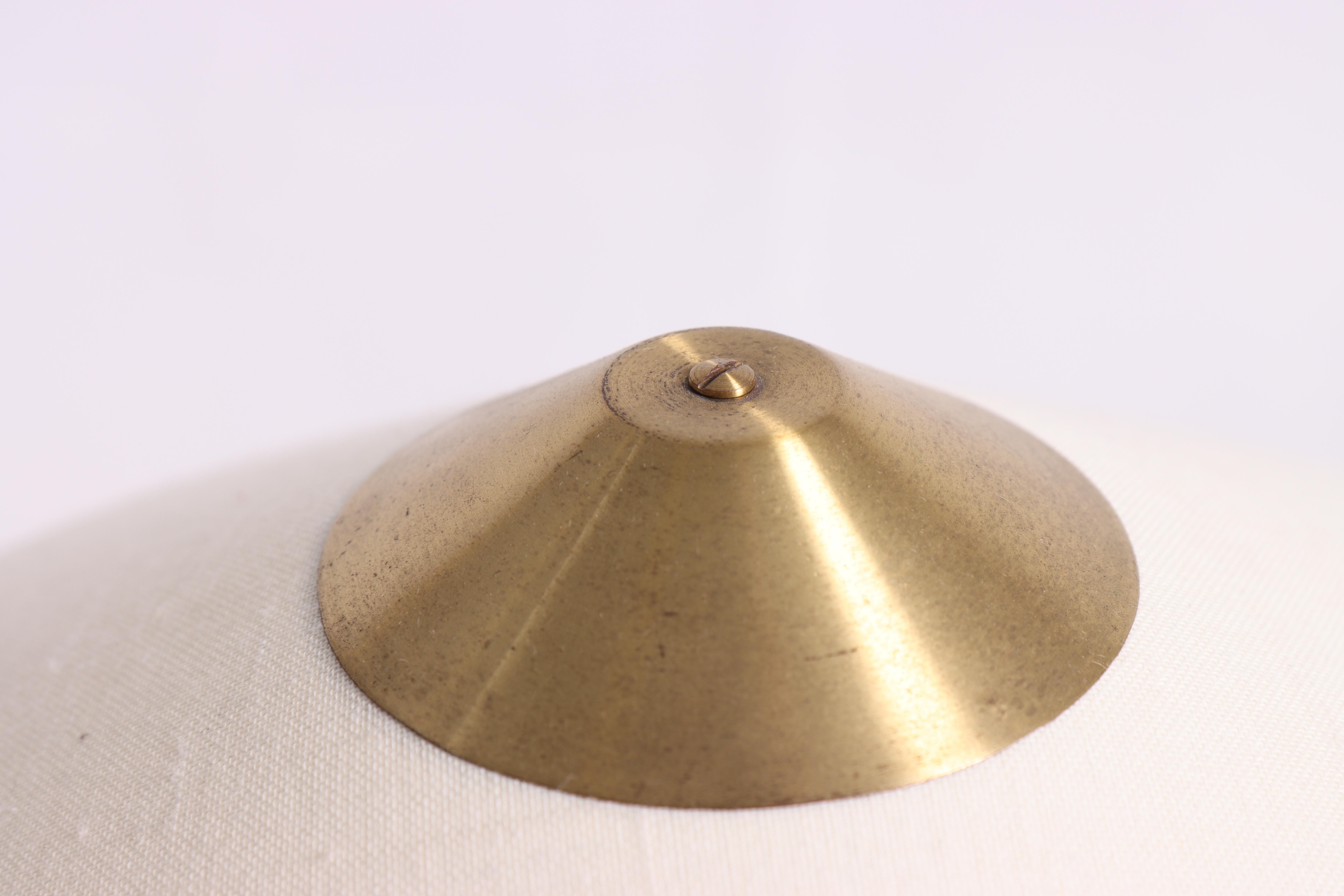 Esta lámpara de sobremesa es un modelo elegante y clásico diseñado por el danés Bent Karlby. La lámpara es de latón, lo que le da un aspecto atemporal y sofisticado. El vástago está parcialmente hecho de madera de teca, lo que añade un elemento