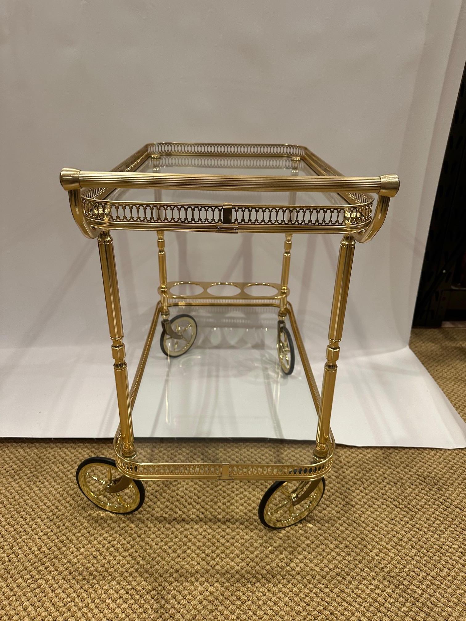 Elegant neoclassical style brass finish bar cart having two tiers, lovely pierced gallery around the top and place for wine bottles on the bottom.  Especially nice wheels.
