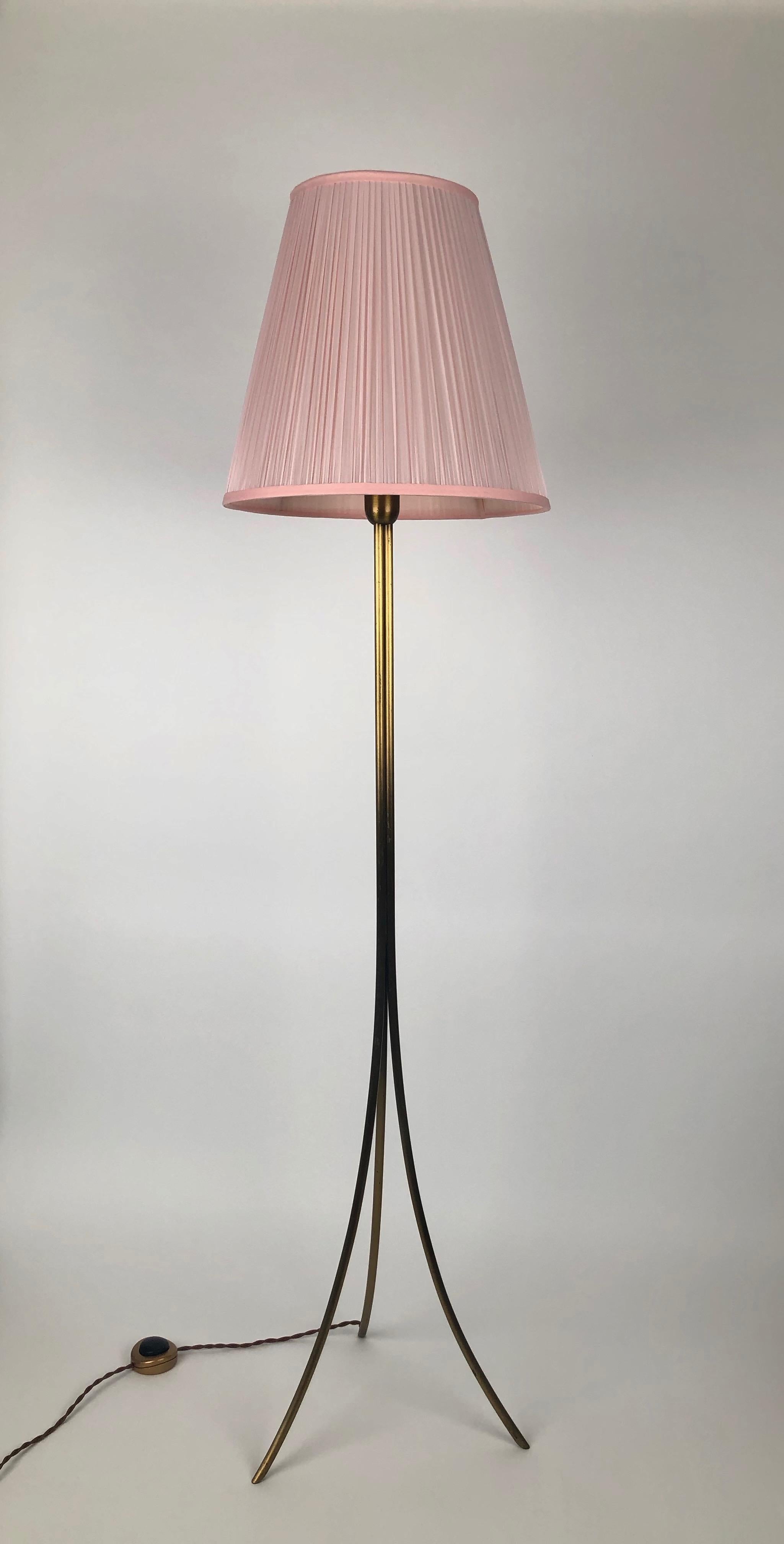 Elegante, dreibeinige Stehleuchte aus Österreich, hergestellt Mitte der 1950er Jahre. Die Metallarbeit ist makellos und hervorragend zusammengesetzt, um eine zarte Form zu schaffen. Dazu passt ein Lampenschirm aus halbtransparenter rosa Seide. Ein