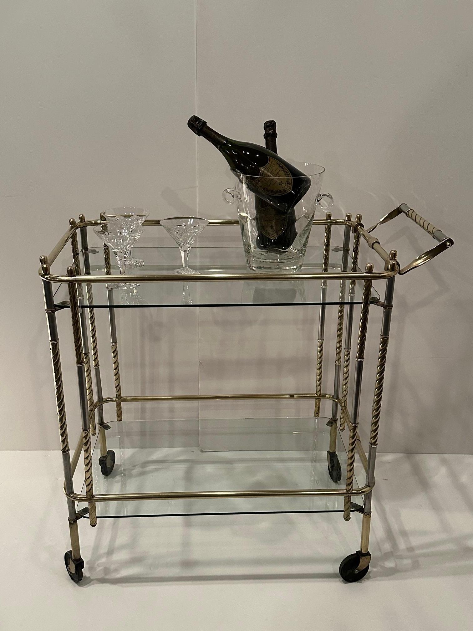 Elegant two tier midcentury modern Italian barcart having a sleek mix of steel, brass and glass.
31” h to handle
Gallery height 31”
Top shelf height is 28.5
Lower shelf to top shelf is 21” space in between