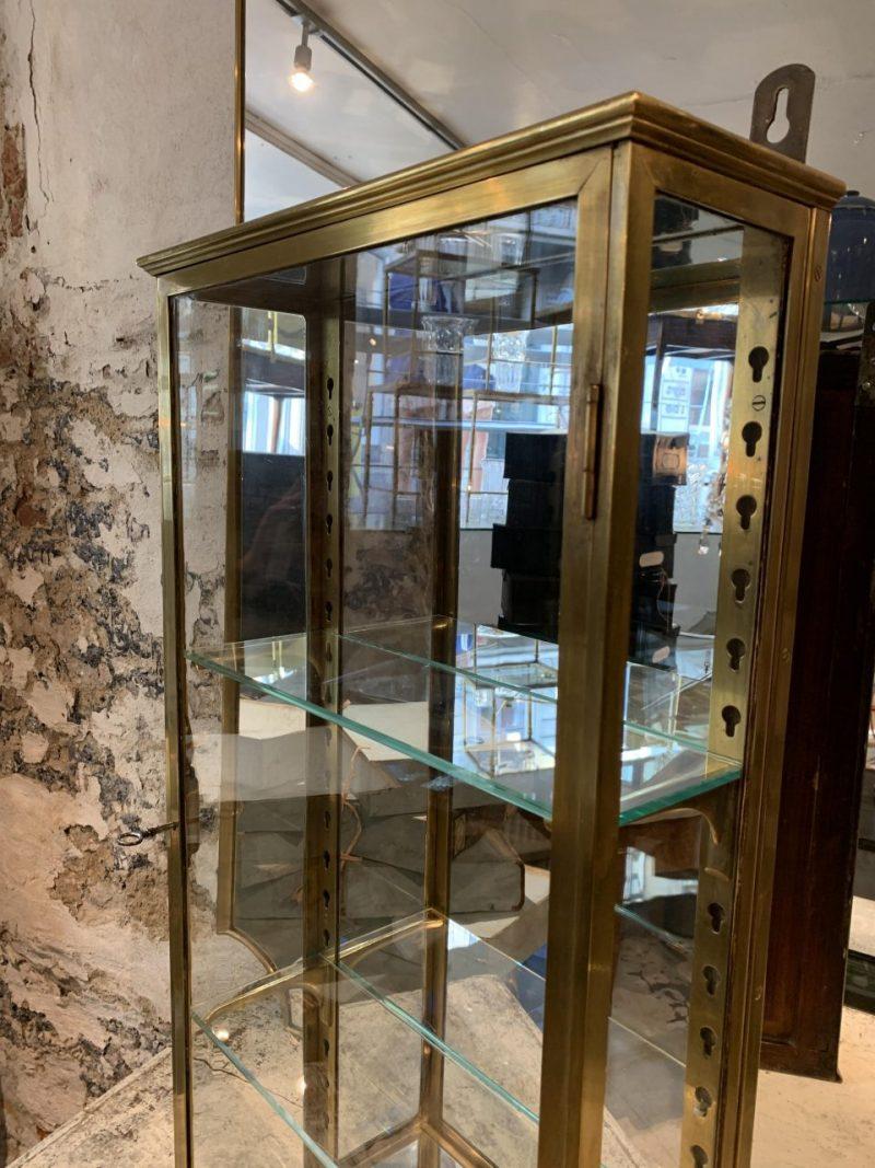 Handsome and presentable brass display wall cabinet, from early 1900s France. Made of quality glass and brass, with 2 adjustable glass shelves, charming old mirrored cladding, and matching lock and key.

The display cabinet is originally boutique