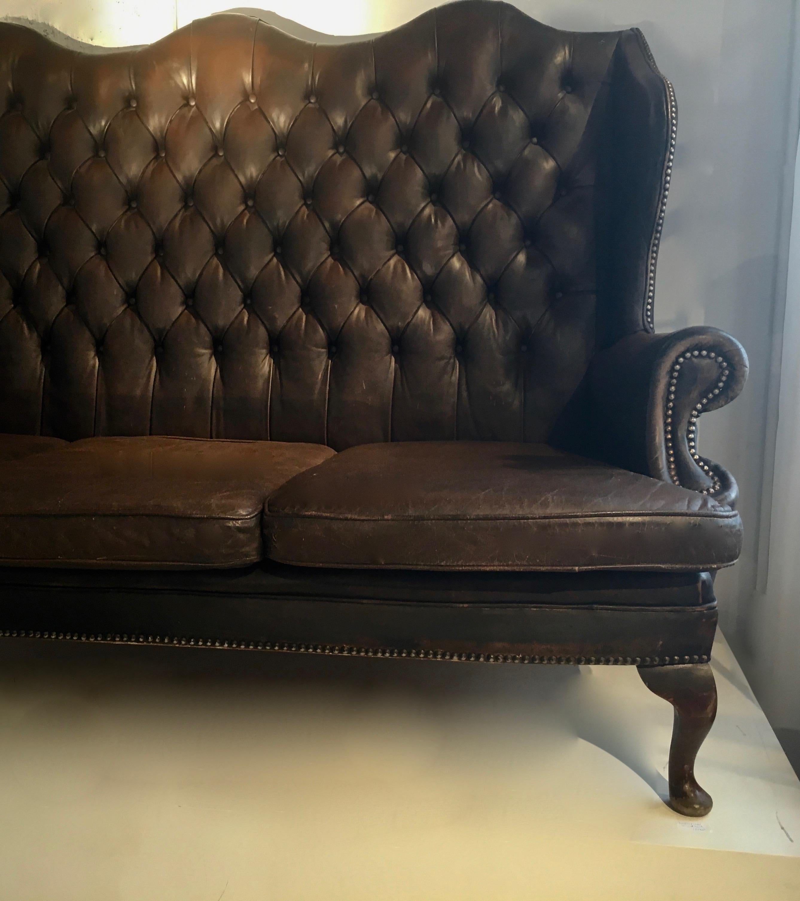 Fine British three seats wingback Chesterfield sofa.
Patinated brown leather,
England, around 1940-1950.