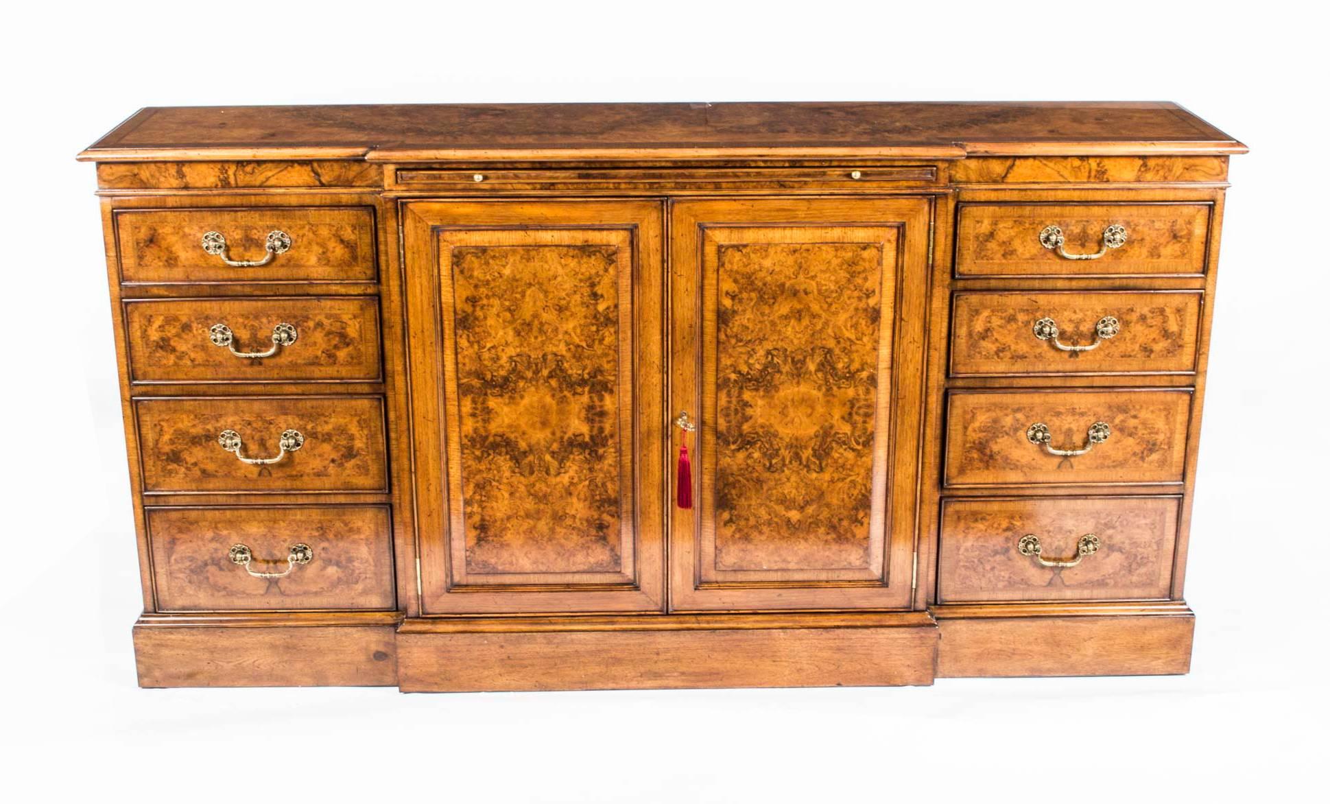 This is a beautiful breakfront burr walnut sideboard with room for all your plates, china, glassware and cutlery, dating from the last quarter of the 20th century.

It features two doors in the centre and a bank of four drawers on either side.

The