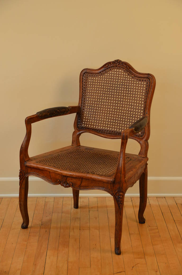 Elegant caned Louis XV period walnut armchair, circa 1760. Leather armrests.