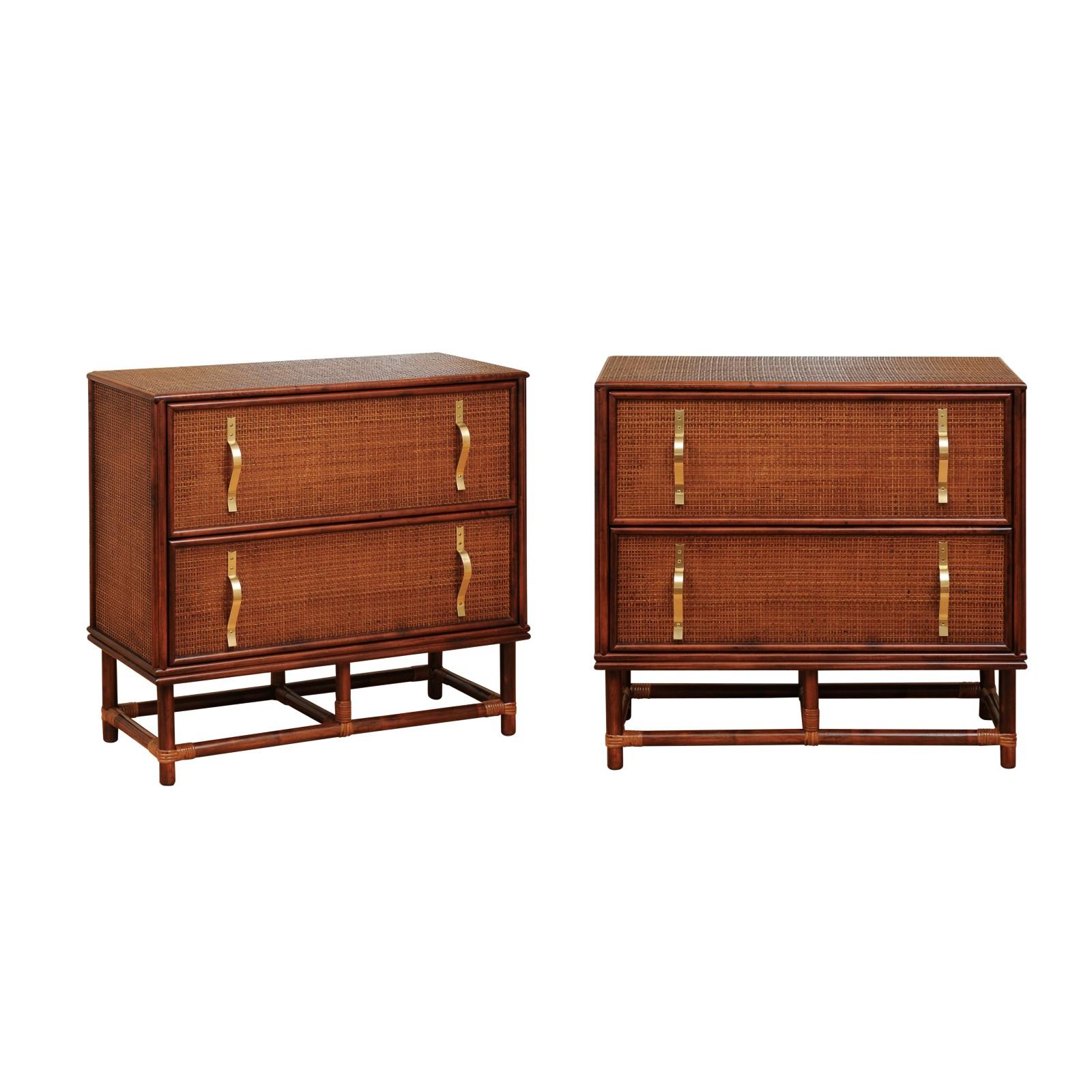 An exquisite meticulously restored vintage two-drawer commode, circa 1955. Stout, exceptionally crafted solid hardwood case construction atop a simple rattan base. The case is veneered in cane with a finished back. The drawers are marked with