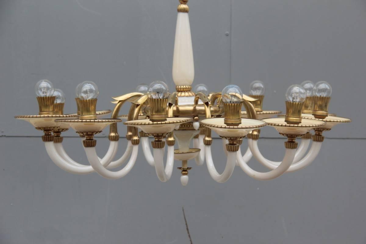 Elegant chandelier in opal glass and 1950s Italian design brass, made entirely by hand by skilled hands of artisans now gone, to note the elegance and sinuosity of the brass pieces.