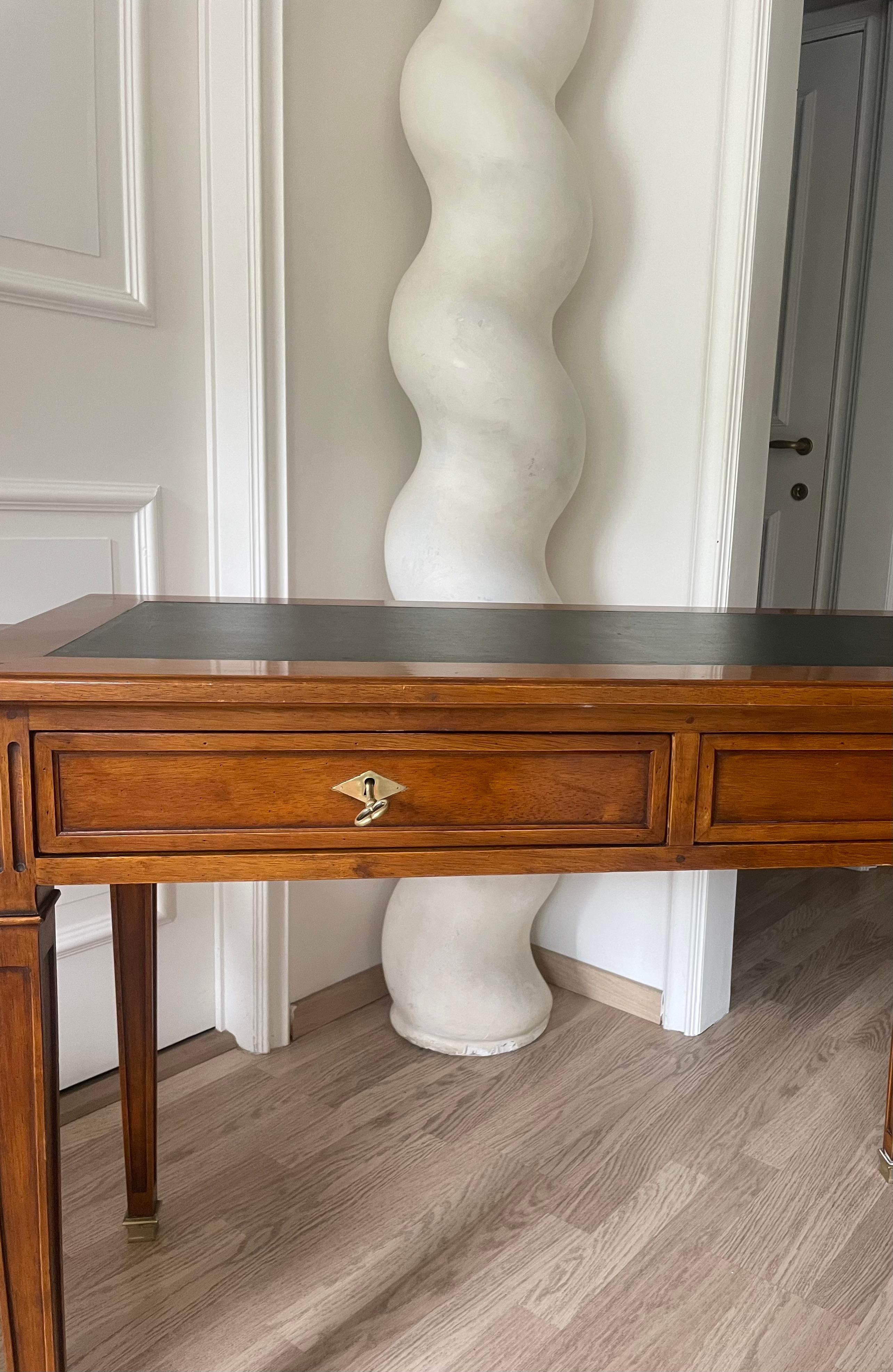 Elegante scrivania in ciliegio in stile Luigi XVI.
Top in pelle nera,  due chiavi in ottone, due cassetti sul davanti e ante di scrittura su ogni lato.
Sabot in bronzo.
Maison Jansen-Paris France 1960
