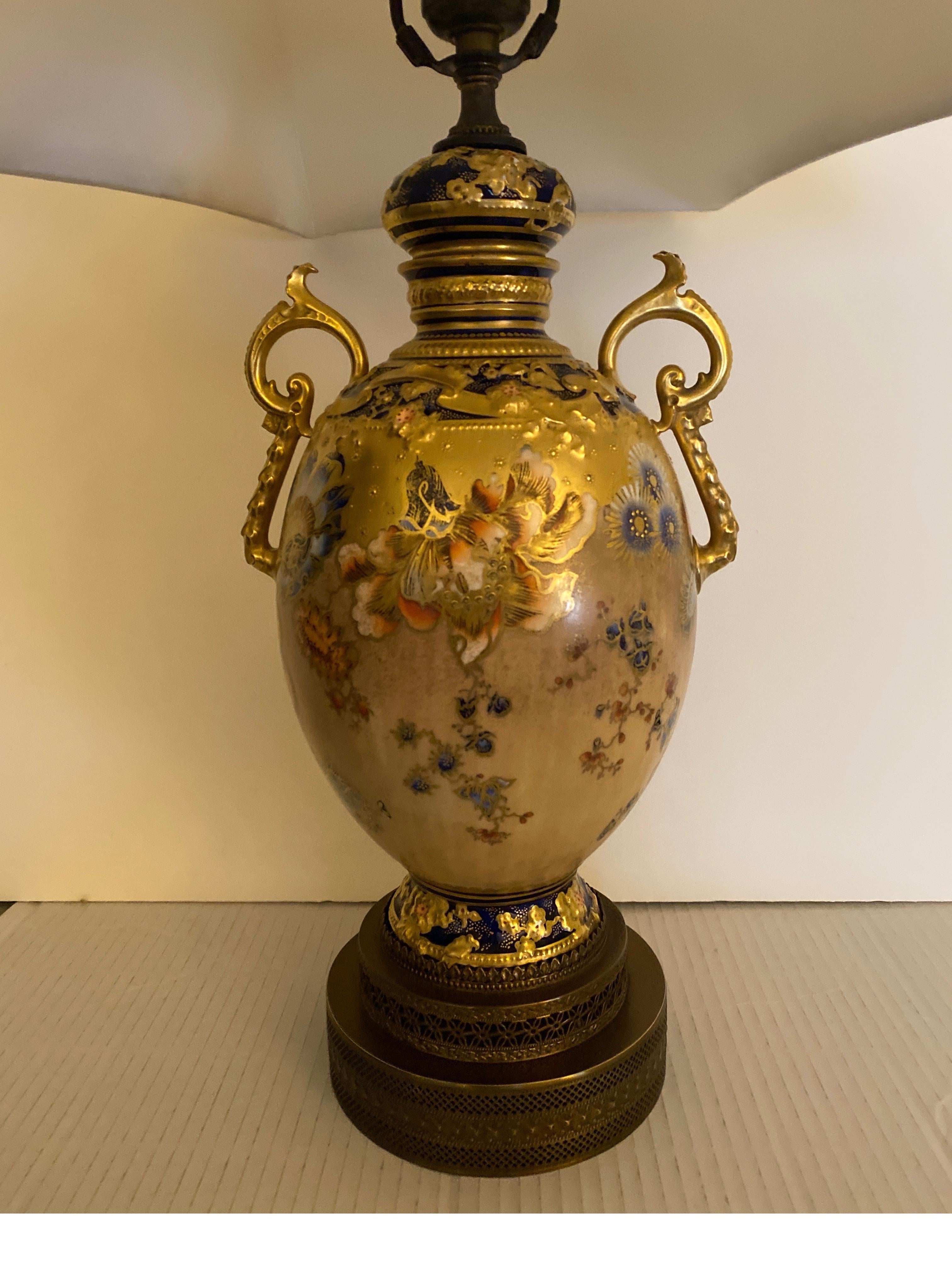 Stunning hand painted and gilt Royal Crown Derby urn now as a lamp. The detailed painted urn with exotic floral decoration with lavish gold trim and cobalt accent color. The porcelain was lamped in the early part of the 20th Century, paired with a