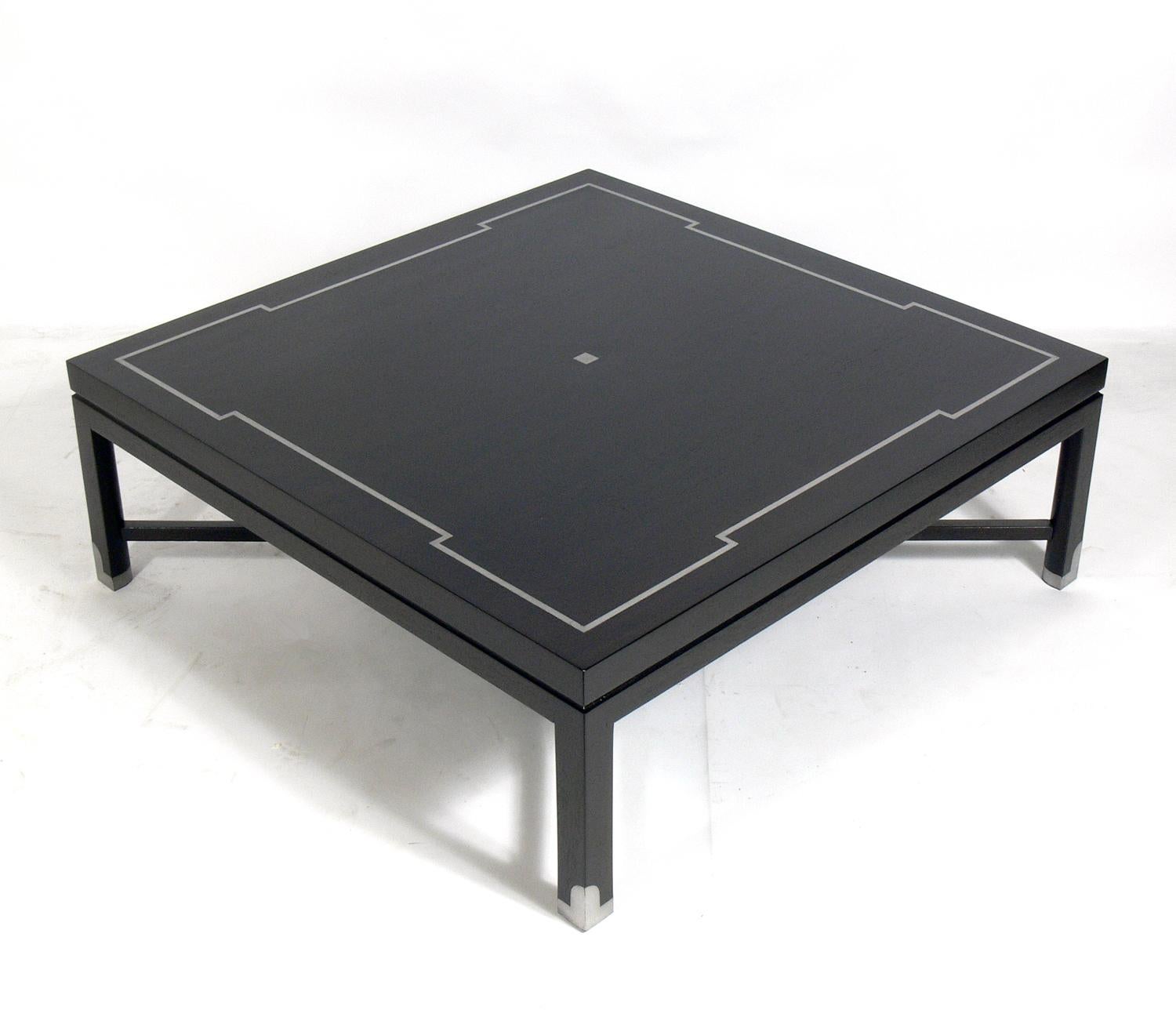 Elegant coffee table, custom made by Tommi Parzinger Originals, American, circa 1960s. It has been refinished in an ultra-deep brown and is inlaid with pewter on the tabletop and the sabots. This large-scale table measures an impressive 42