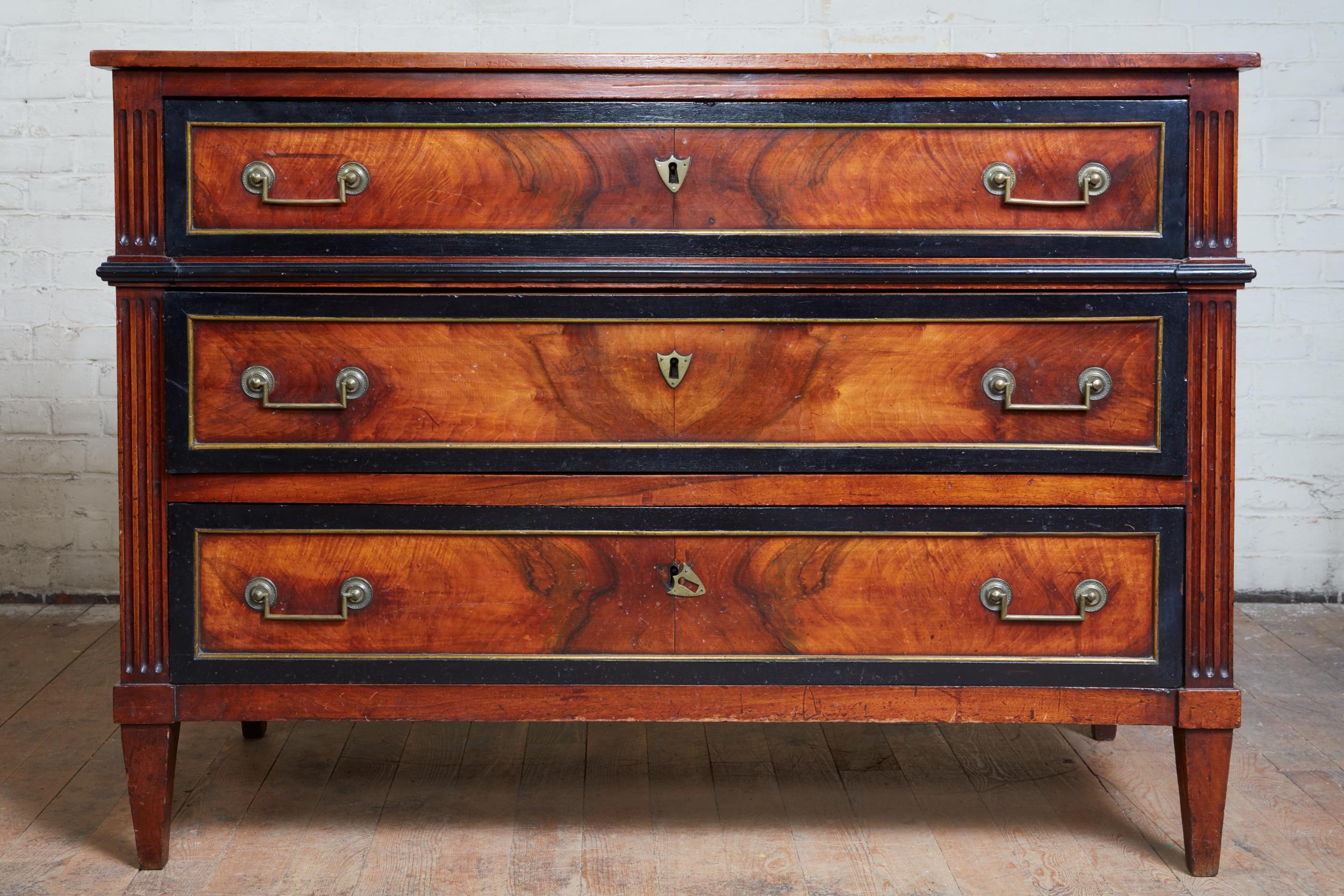Fine French walnut, ebonized fruitwood and brass-mounted neoclassical commode, the simple top over three drawers, having elegant hip molding between the first and second, all with ebonized fruitwood moldings and brass trim and original brass