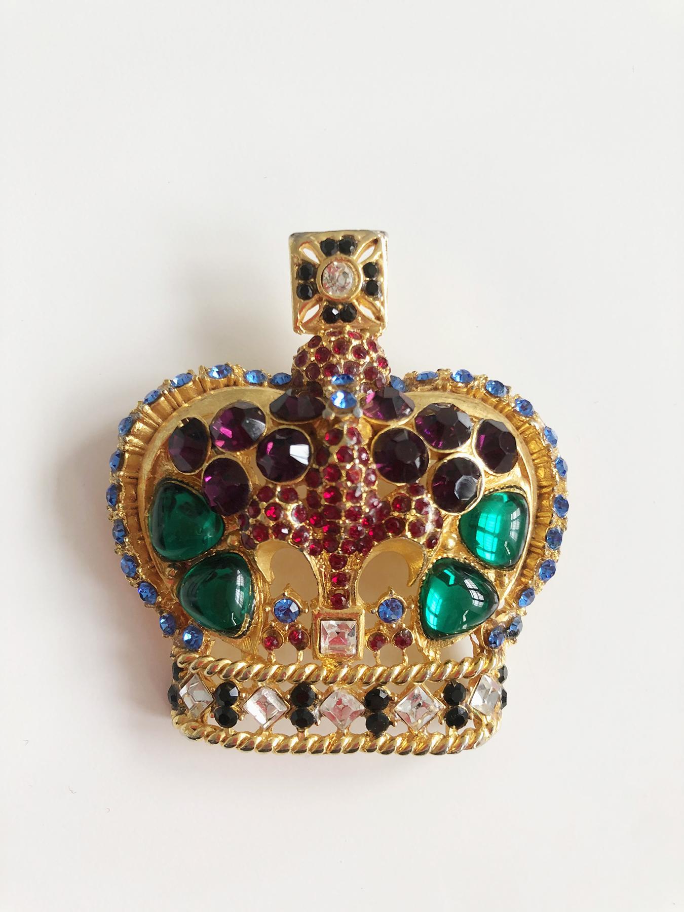 Beautiful brooch by Gianni Versace embellished with a lily and surmounted by a cross.

It is made of gilded metal with inlaid and poured crystal gems: sapphire crystals cabochon blue, green, red, purple and transparent

Very delicate work of setting