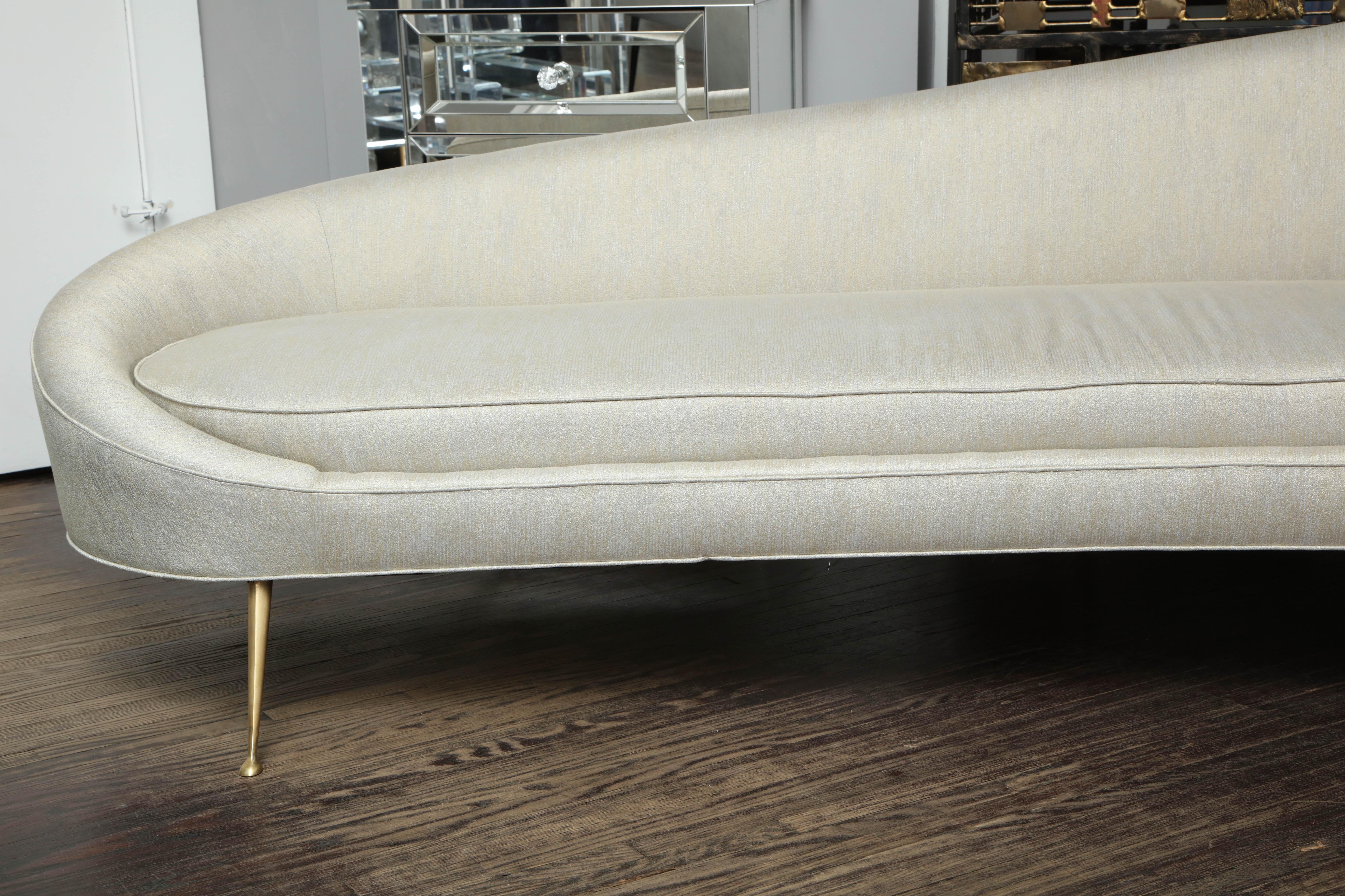 Elegant curved sofa in custom upholstery with brass legs. Customization is available in different sizes, finishes and fabrics.