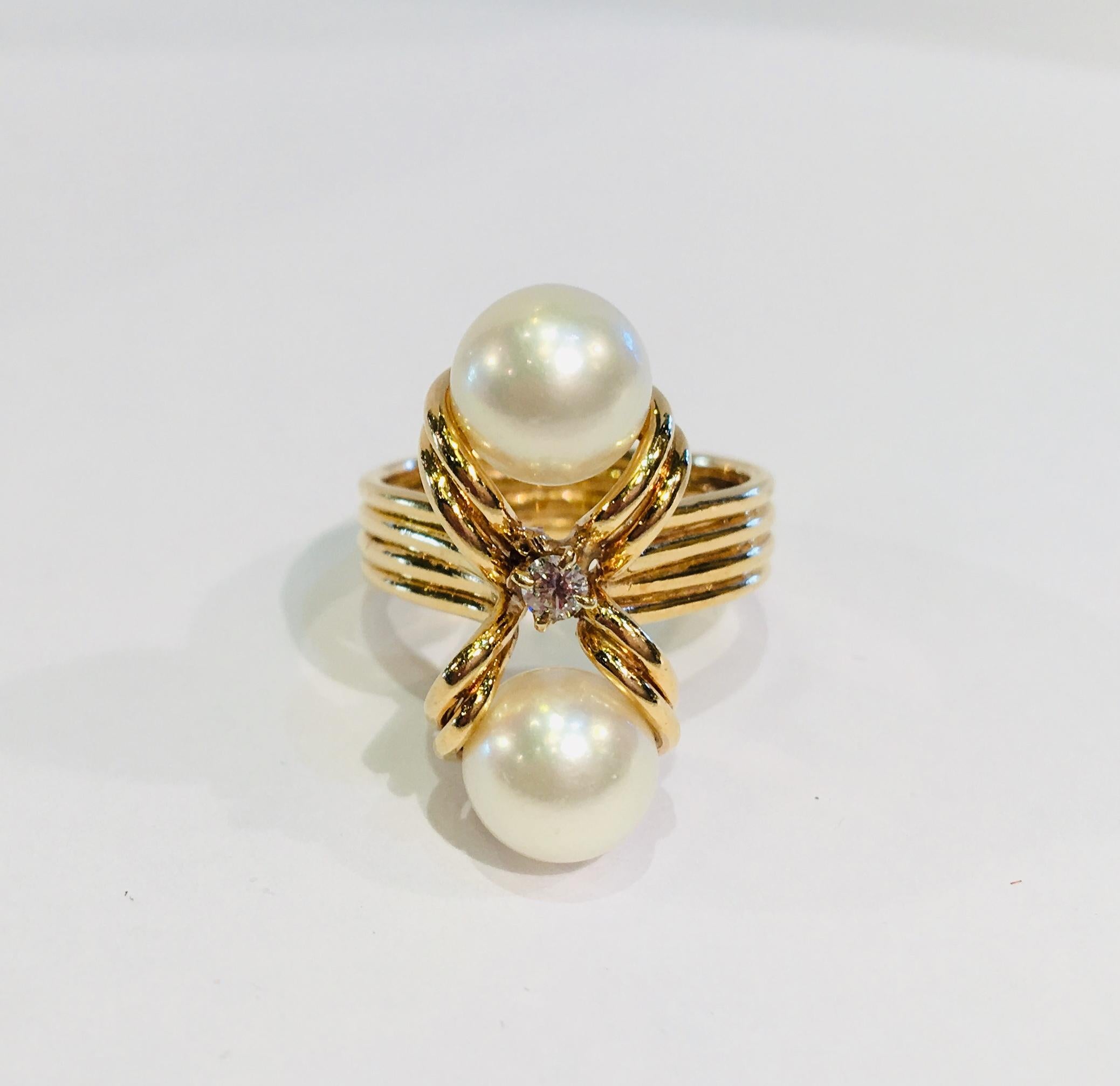 Beautifully proportioned, custom-made, 18 karat yellow gold estate ring features a pair of 2 round white cultured pearls with a beautiful luster, separated by an 