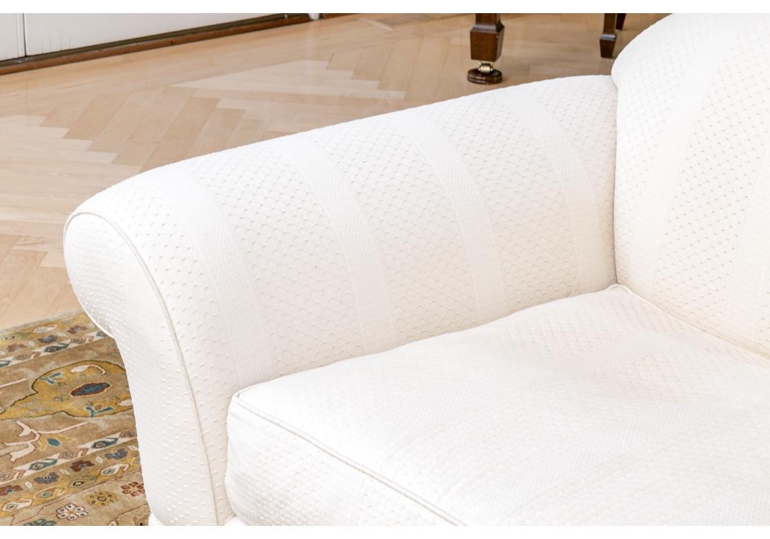 A well made and stylish curve back Loveseat with wide flat panel arms, skirted with four custom  toss pillows. The fabric is a deceptively simple yet intricate quilted type with tiny repeating geometric honeycombed motif. Very well made and quite