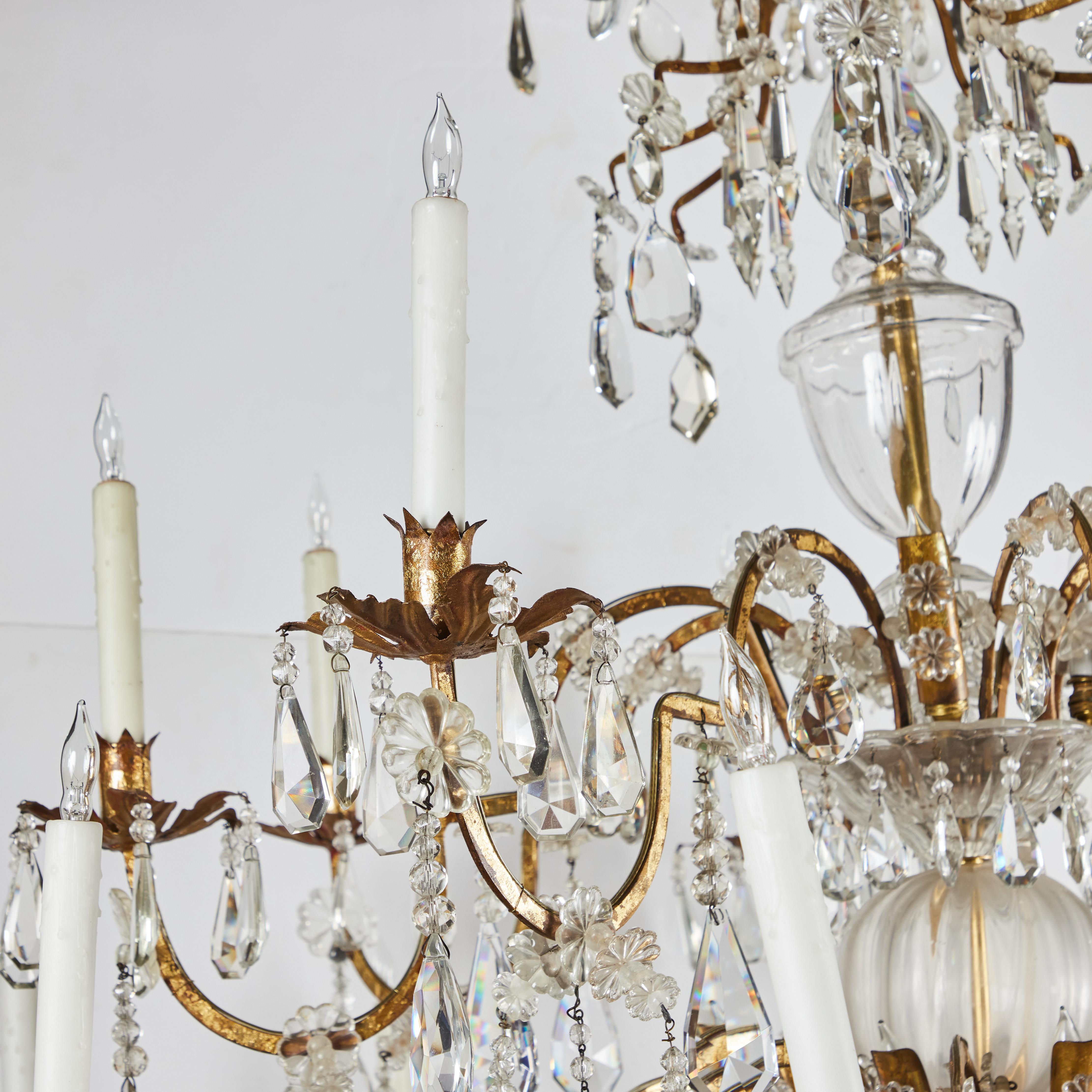 An elegant and dramatic, 28 light cut crystal and gilded metal and tole chandelier.  The center shaft consisting of crystal spheres that lead to a pear shaped crystal fob.