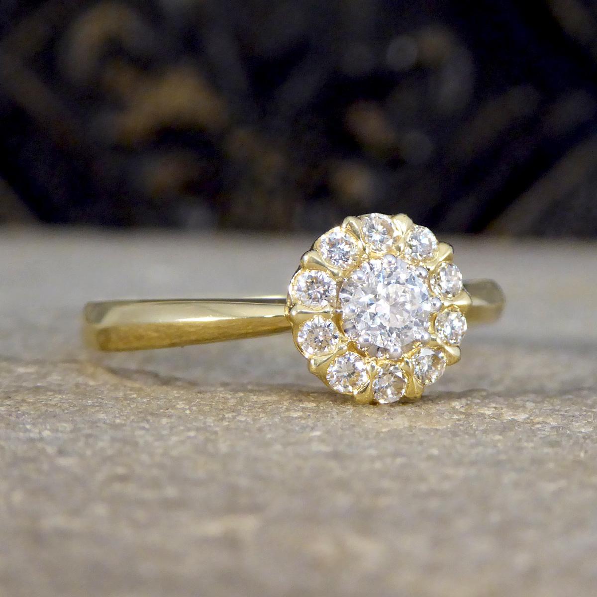 Dieser atemberaubende Daisy-Diamant-Cluster-Ring ist ein Meisterwerk an Eleganz und Handwerkskunst, gefasst in 18 Karat Gelbgold. Dieser Ring ist mit einem Brillanten in der Mitte besetzt, der von rhodinierten Spangen gehalten wird. Die Verwendung