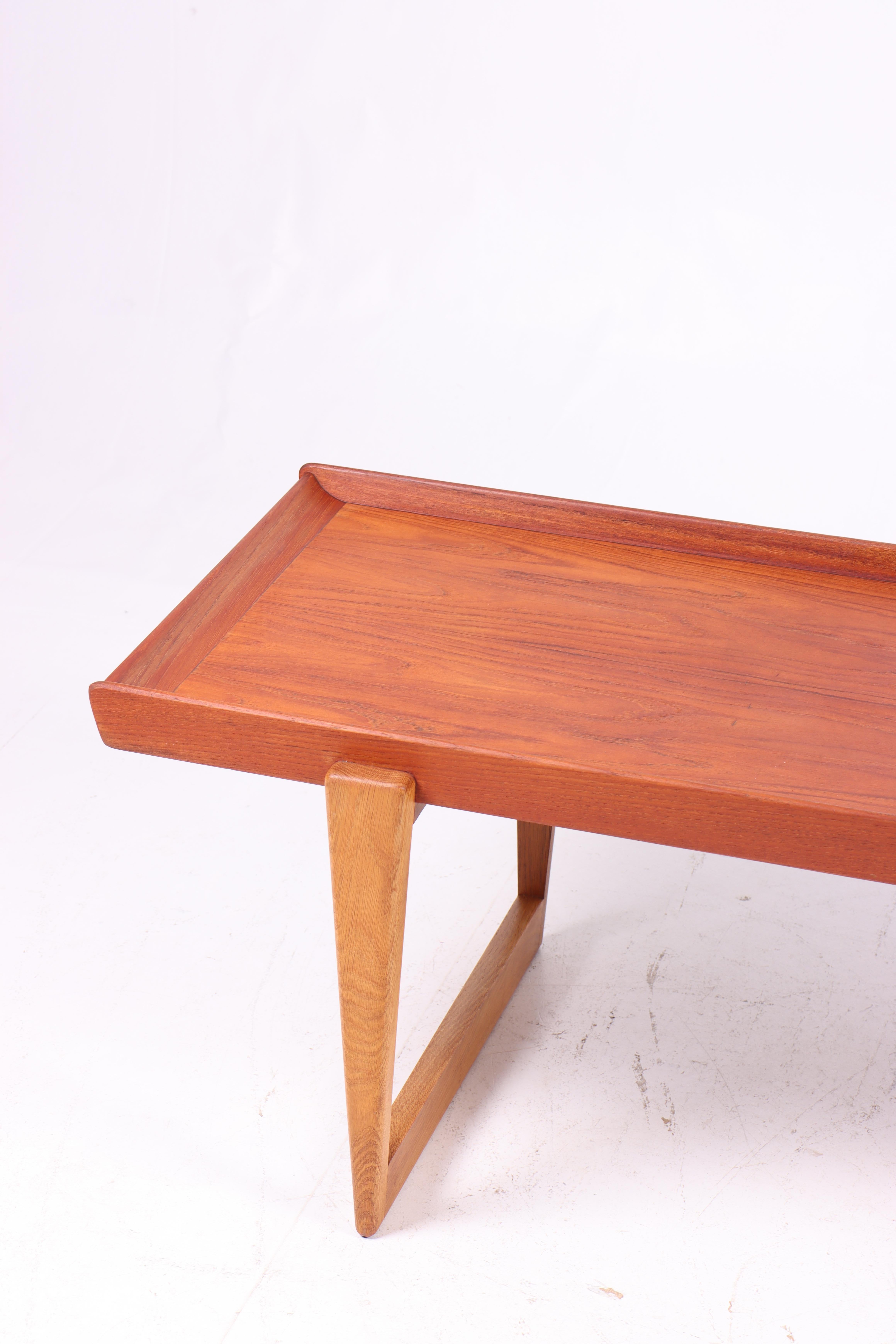 This coffee table is an elegant and timeless piece of furniture, designed and produced in Denmark in the 1960s. The tabletop is made of beautiful teak wood, featuring a warm and glowing finish that highlights the natural grain of the wood. The