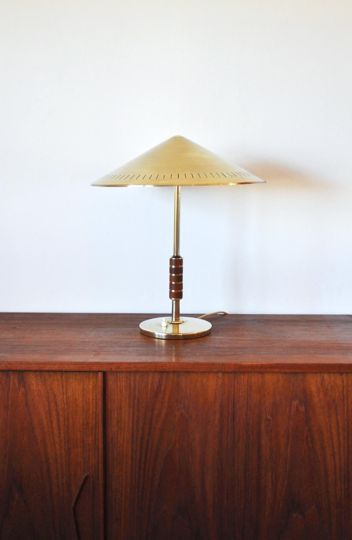 Elegant Danish brass table lamp from Lyfa 1956 designed by Bent Karlby. Model B146. Solid brass with two-light sources, stem decorated with five pieces of teak. 
Nicely patinated condition, polished and inner shade new painted. 
Light source: E27