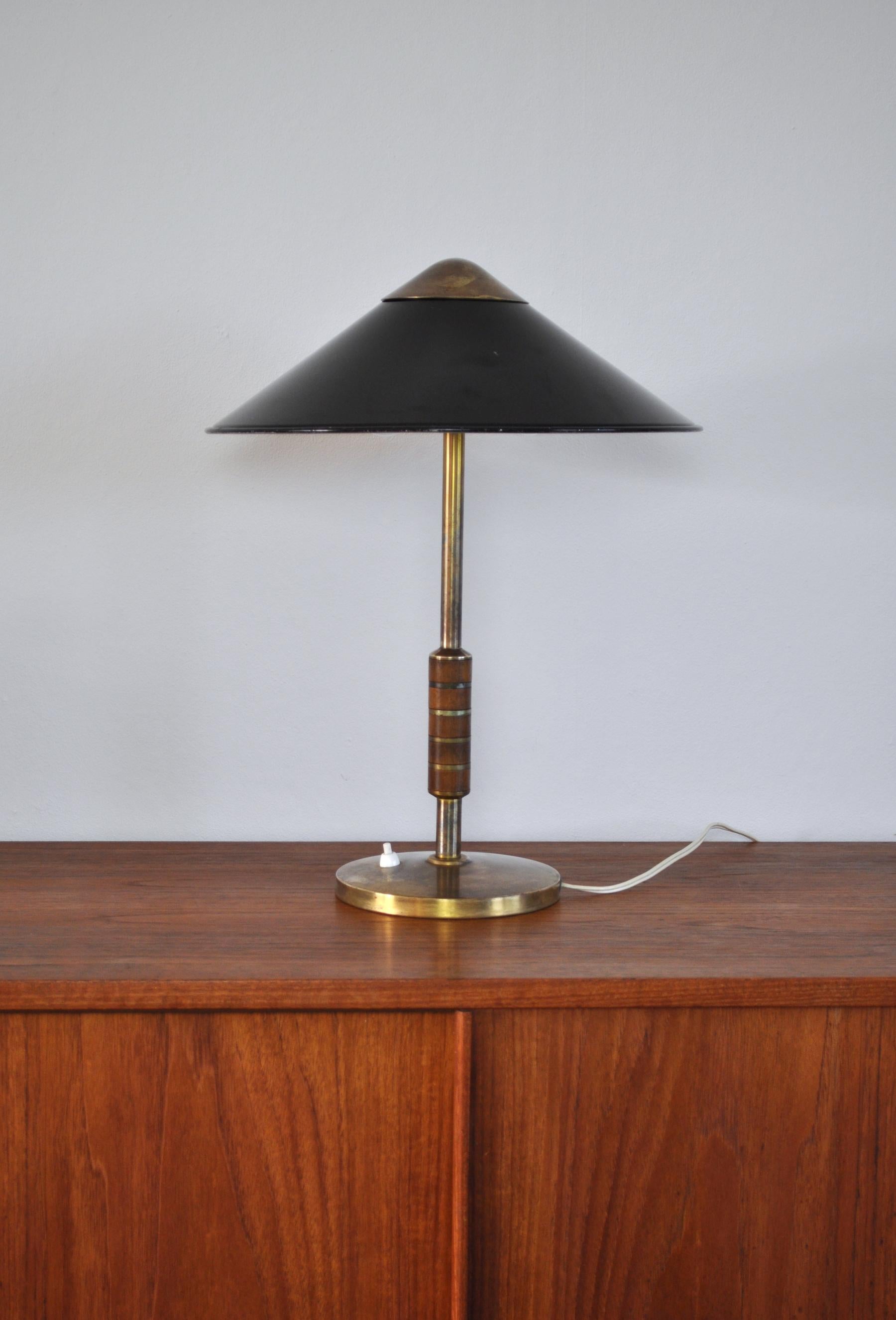 Elegant Danish brass table lamp from Lyfa designed by Bent Karlby 1956. Model B146. Solid brass with two-light sources, stem decorated with five pieces of teak. Shade black lacquered outside, white inside, top in brass. 

Untouched patinated