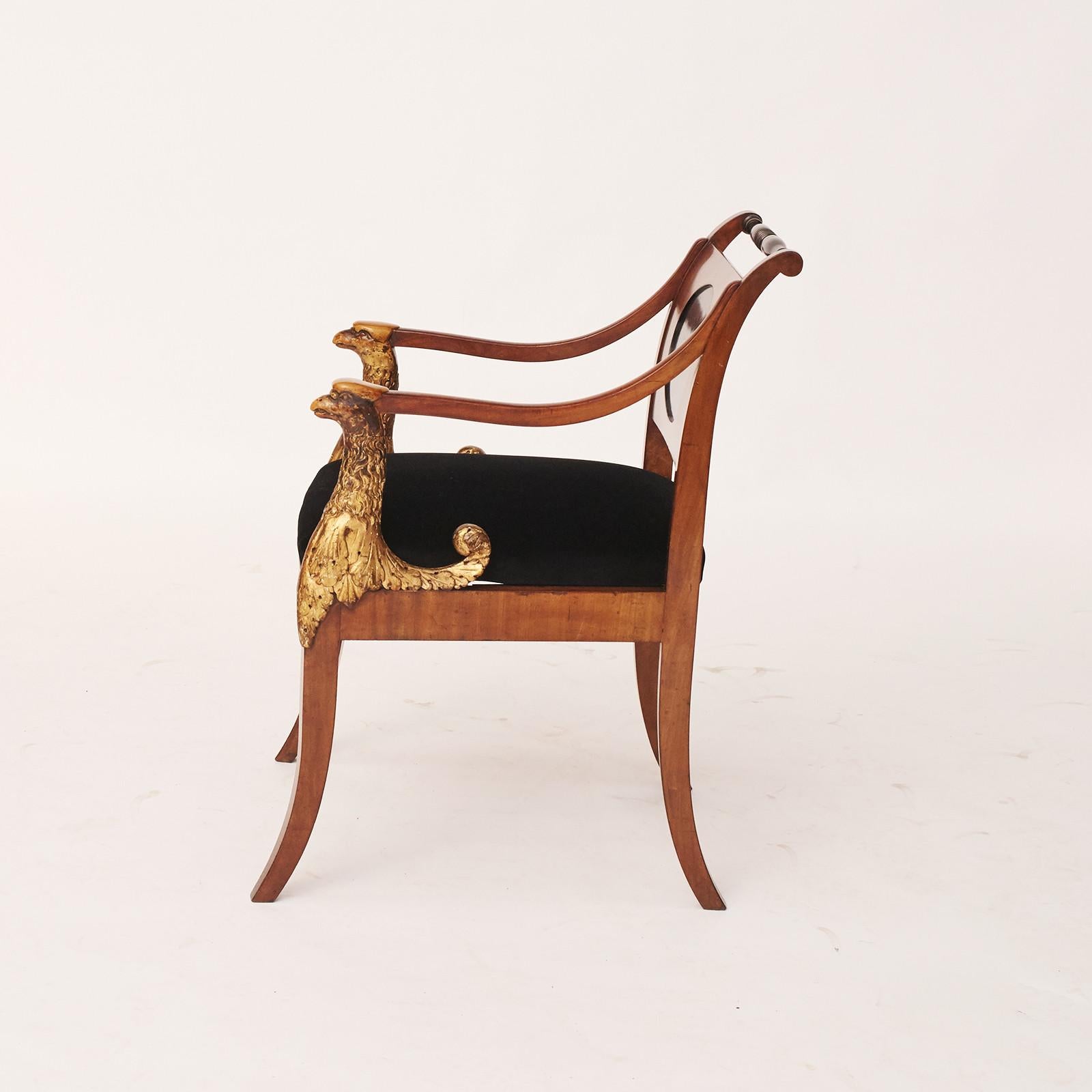Eleganter und dekorativer Empire-Sessel. Hergestellt aus Mahagoni, mit Intarsien aus hellem Holz (Zitronenbaum). Ovale Rückwand aus ebonisiertem Holz. Vorderseite der Arme in Form von hölzernen, geschnittenen Greifern mit Originalvergoldung. Loser