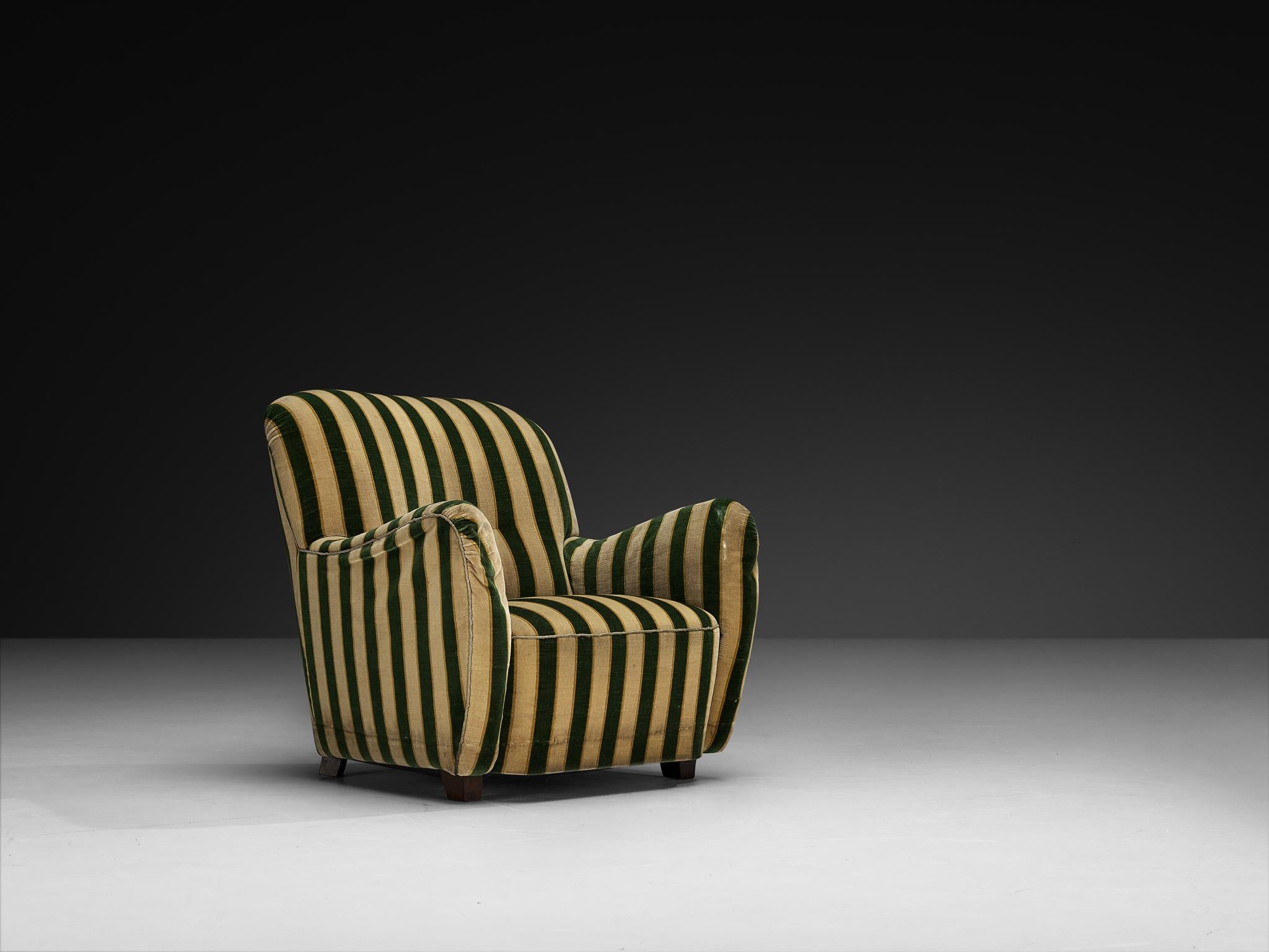 Lounge chair, fabric, beech, Denmark, 1940s

A charming Danish lounge chair from the 1940s, radiating warmth and character. Upholstered in a lively striped fabric in green and beige, the chair features a gently rounded silhouette that invites