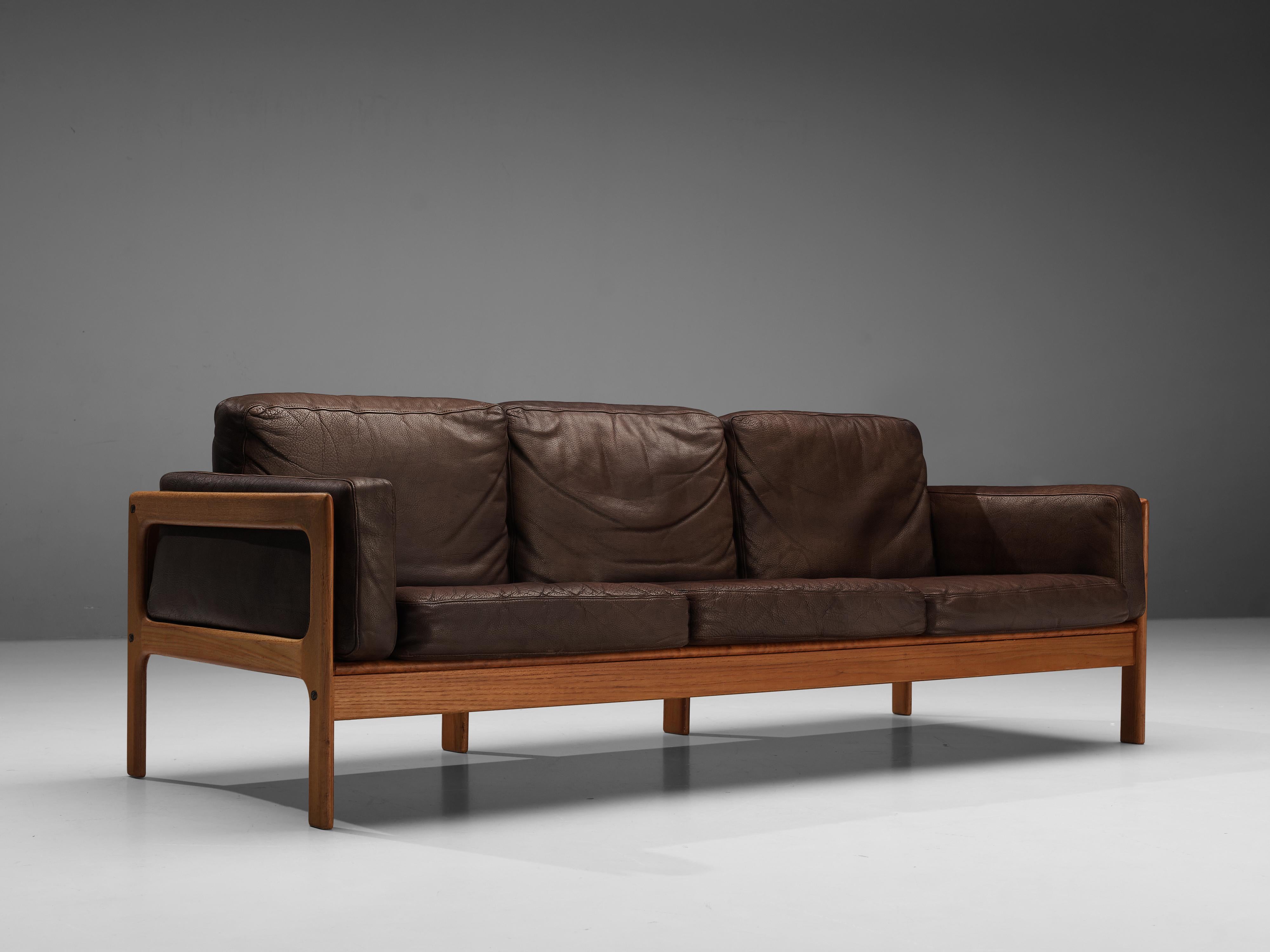 3-seat sofa, leather and stained oak, Denmark 1960s. 

Sturdy Danish sofa in brown leather. This sofa has an inviting, comfortable look while still being stylish. The very well-crafted wooden frame and legs fit perfectly with the brown leather,