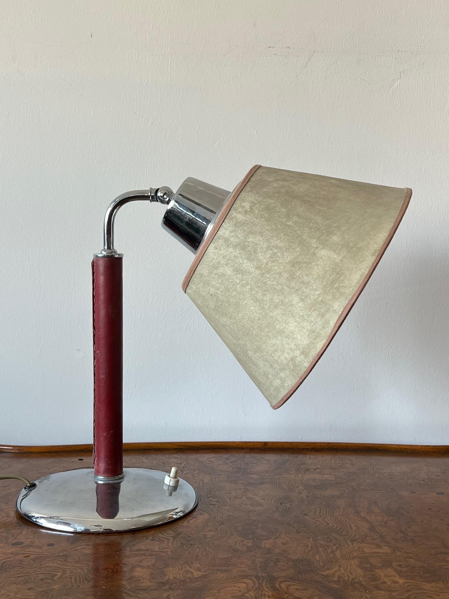 Lampe de table/bureau inhabituelle avec tige recouverte de cuir rouge, abat-jour original en parchemin, laiton chromé.
Une autre caractéristique est que l'abat-jour peut être relevé pour devenir un éclairage vers le haut.