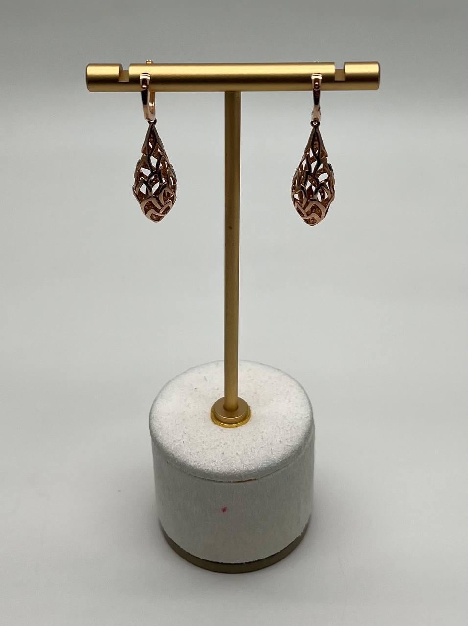 Une paire de boucles d'oreilles sophistiquée, conçue avec un design ajouré complexe. Les boucles d'oreilles présentent un délicat motif de treillis, accentué par des pavés de diamants scintillants. L'élégante forme en goutte d'eau est suspendue à un