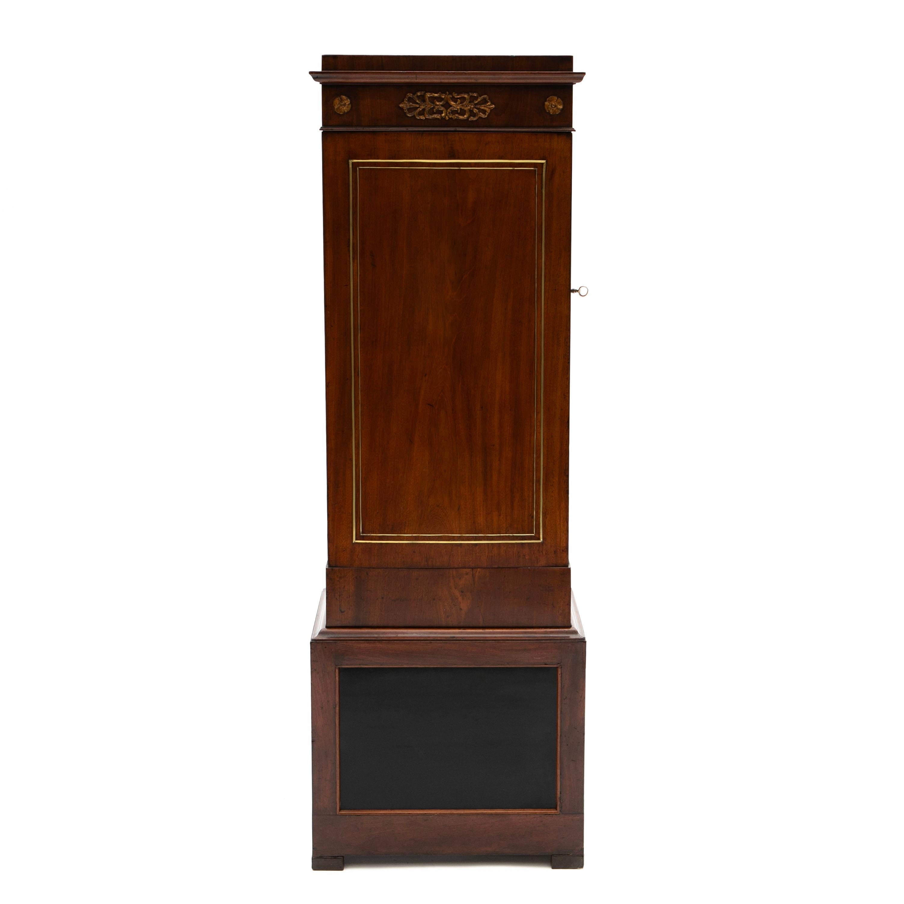 Elegant, architectural Empire pedestal cabinet in 2 parts, crafted in mahogany.
Features a frieze with ormolu mounts of typical Empire period over a cupboard door that opens to reveal a shelved interior and the whole raised on a on a tall pedestal