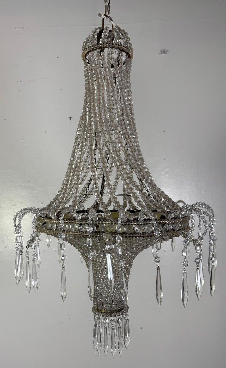 This refined Empire-style chandelier exudes understated opulence with its graceful silhouette and cascading strands of faceted crystal beads. Likely of French or Northern European origin, circa 1920s–1930s, it embodies the neoclassical revival that
