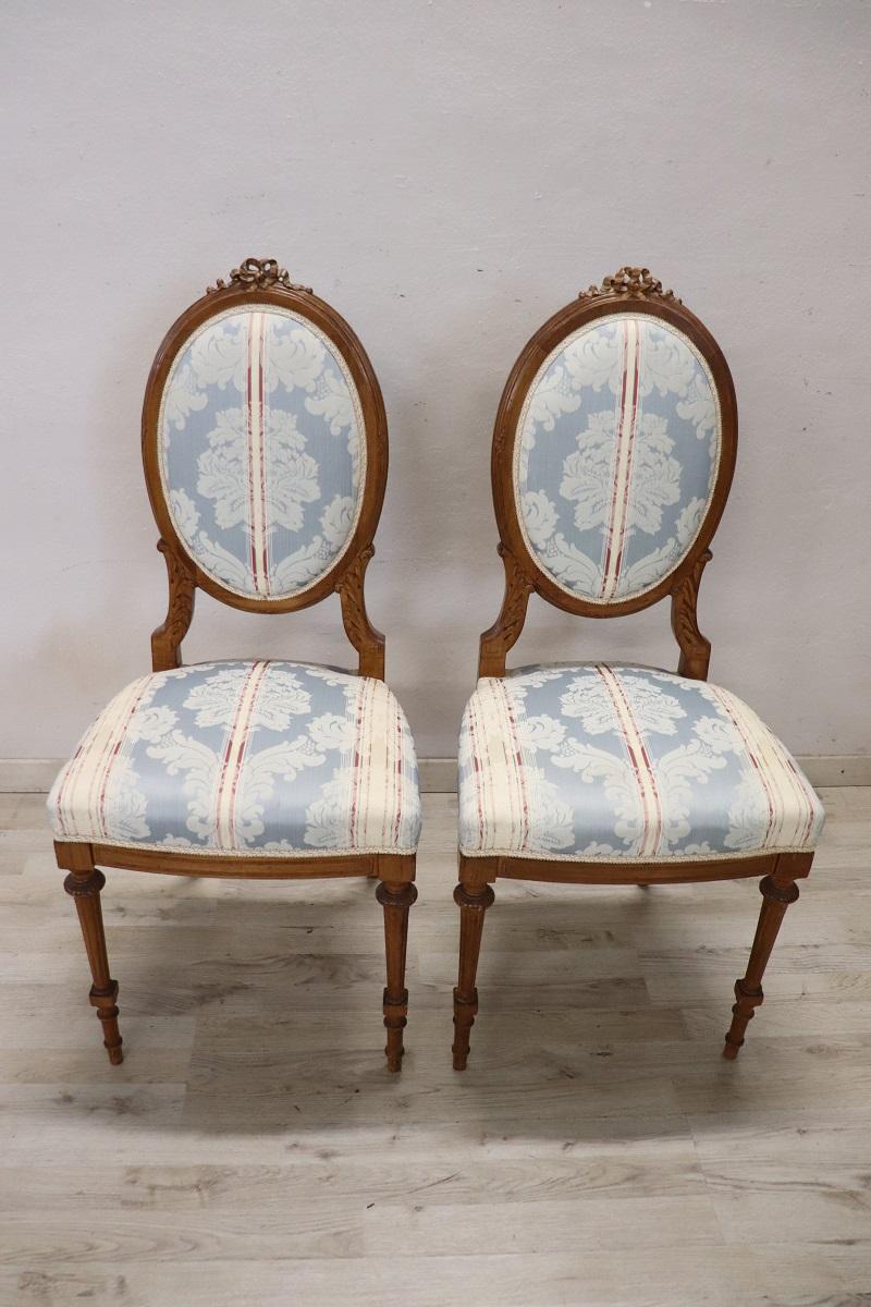 Refined italian Louis XVI style chairs, set of two. The chairs made in solid beech wood. The seat and backrest are comfortable and padded, covered with elegant fabric decorated with a damask pattern. The wood has refined carved decorations. Perfect